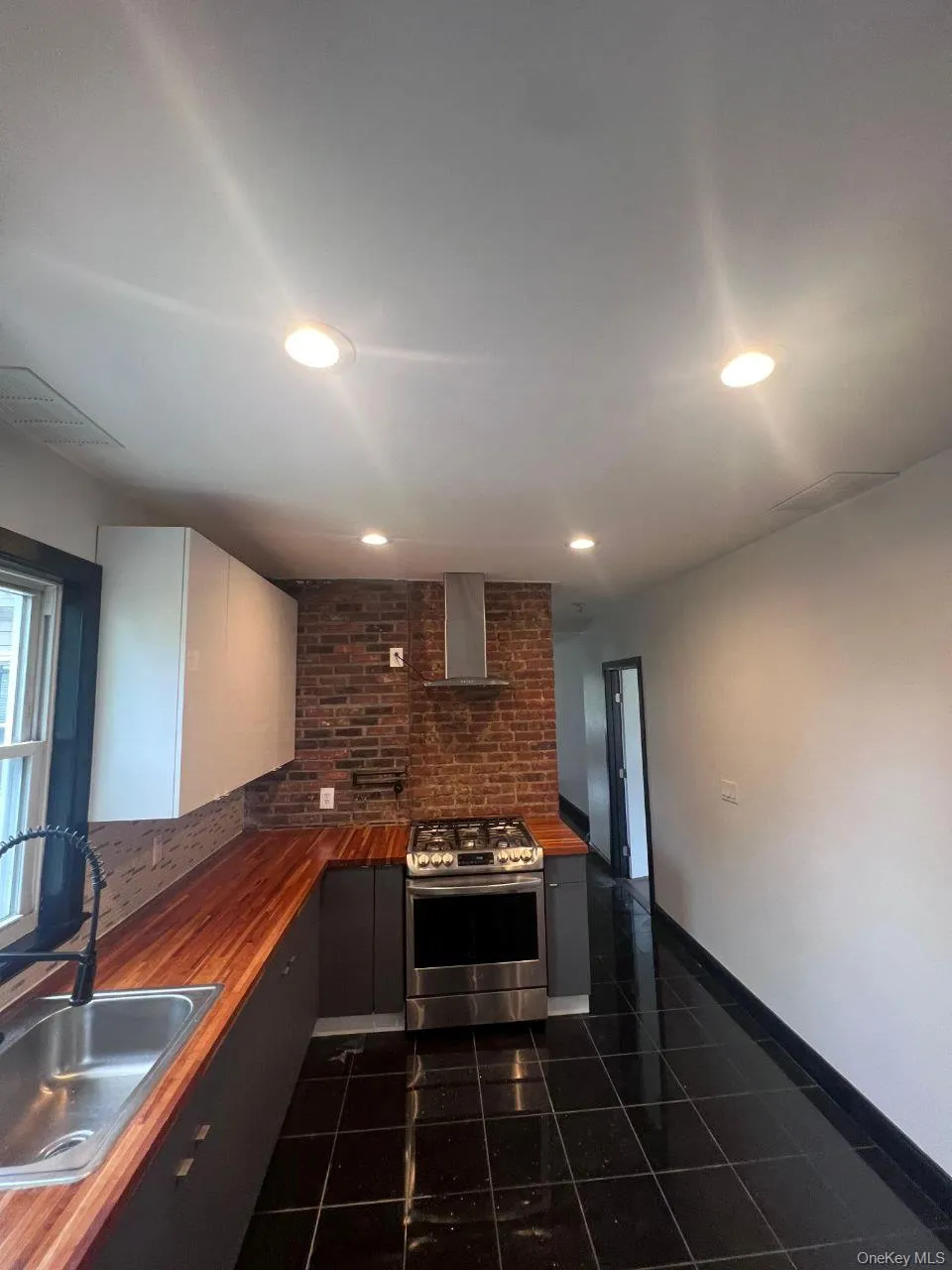 Kitchen featuring gas stove, butcher block counters, wall chimney range hood, recessed lighting, and decorative backsplash Kitchen featuring gas stove, butcher block counters, wall chimney range hood, recessed lighting, and decorative backsplash