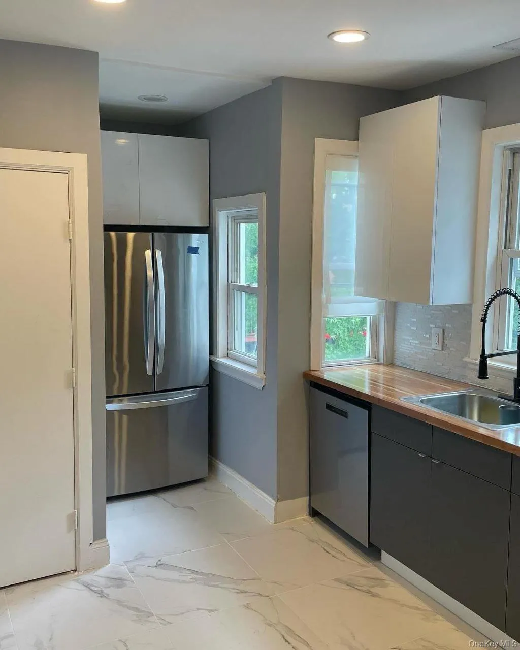 Kitchen featuring stainless steel appliances, light marble finish flooring, modern cabinets, recessed lighting, and white cabinetry Kitchen featuring stainless steel appliances, light marble finish flooring, modern cabinets, recessed lighting, and white cabinetry