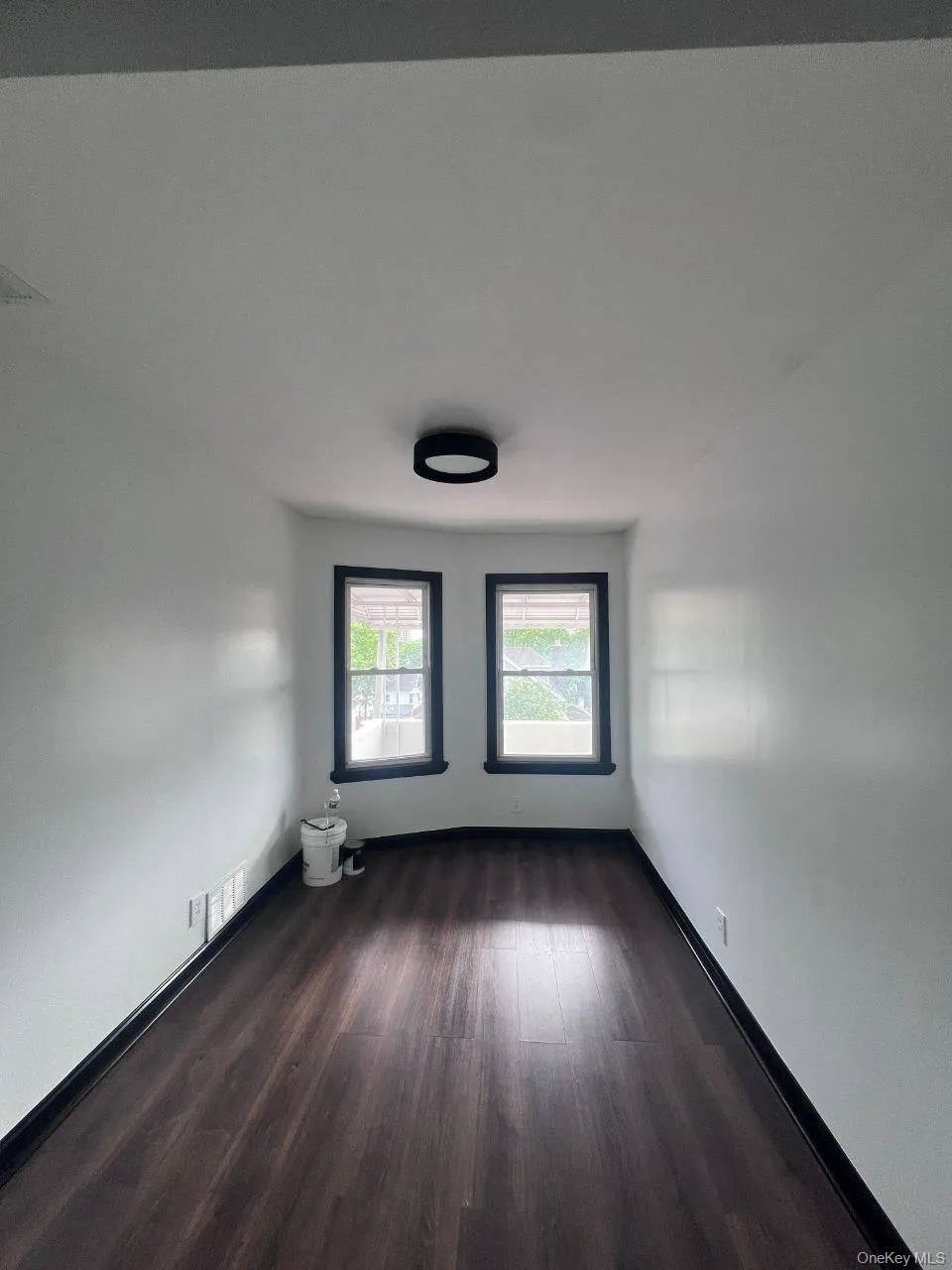 Empty room with dark wood-style floors and baseboards Empty room with dark wood-style floors and baseboards
