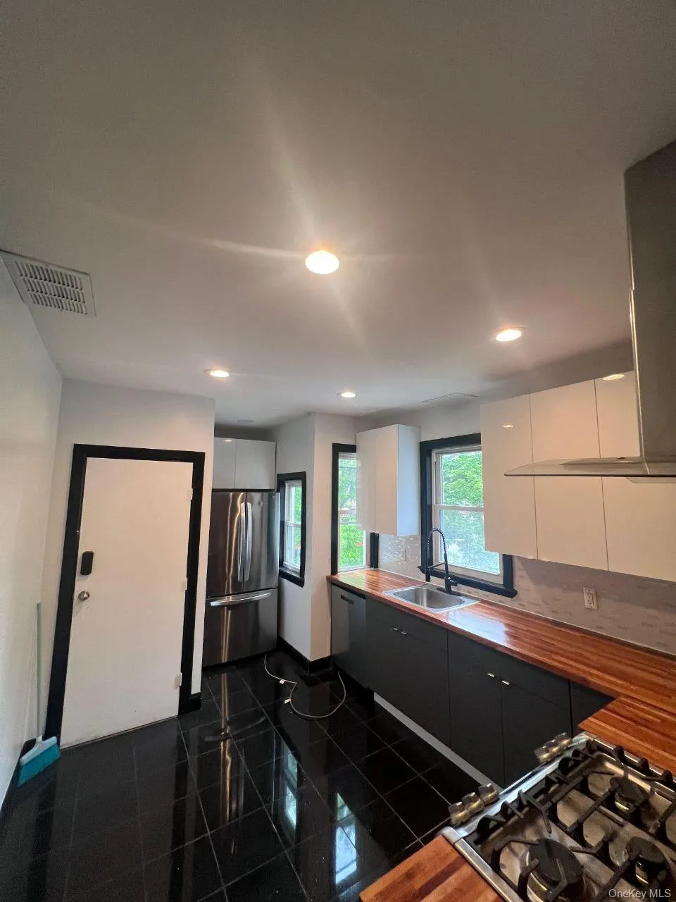 Kitchen with white cabinets, appliances with stainless steel finishes, exhaust hood, recessed lighting, and granite floors Kitchen with white cabinets, appliances with stainless steel finishes, exhaust hood, recessed lighting, and granite floors
