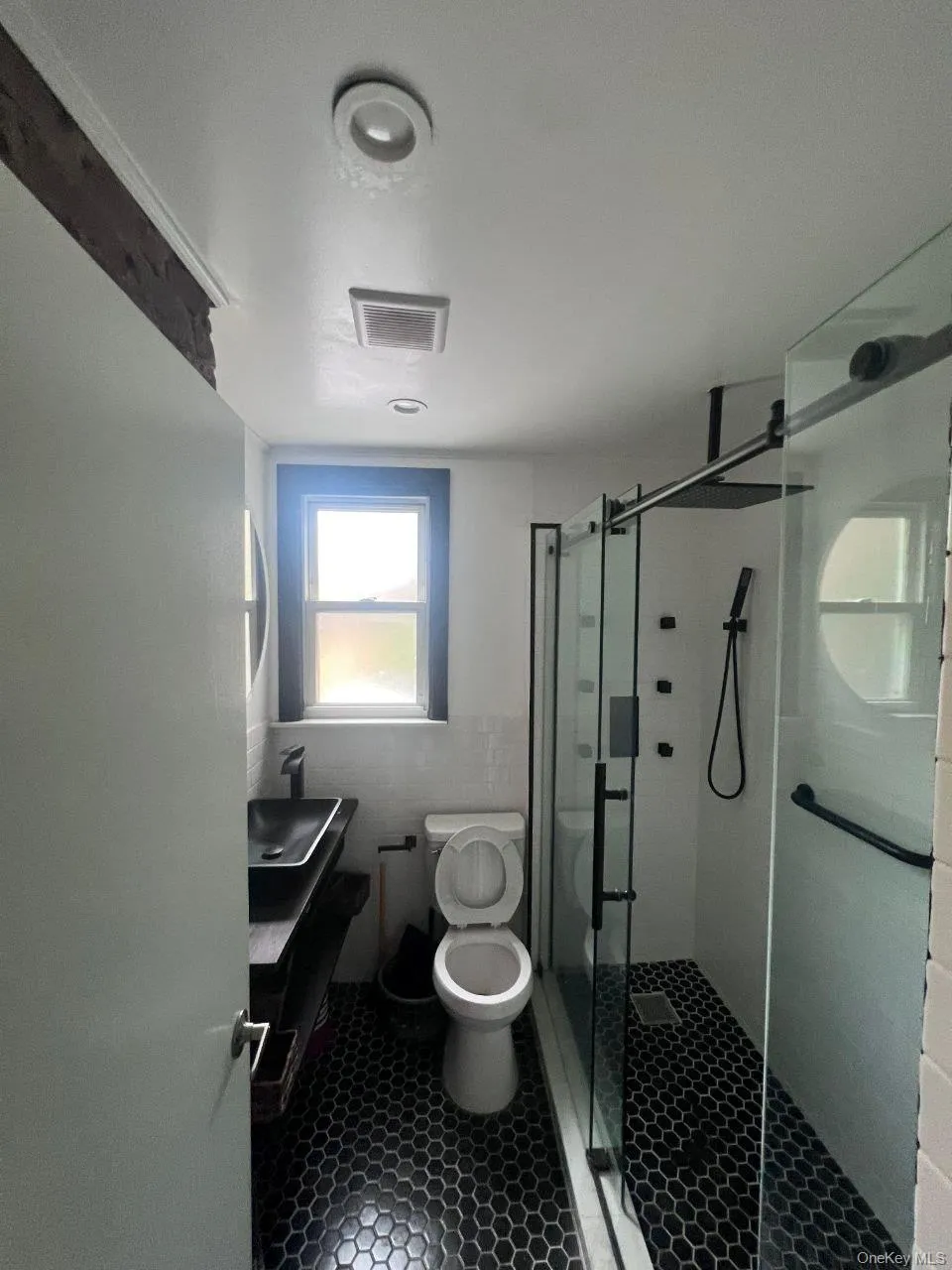 Bathroom with vanity, a stall shower, tile walls, and dark tile patterned flooring Bathroom with vanity, a stall shower, tile walls, and dark tile patterned flooring