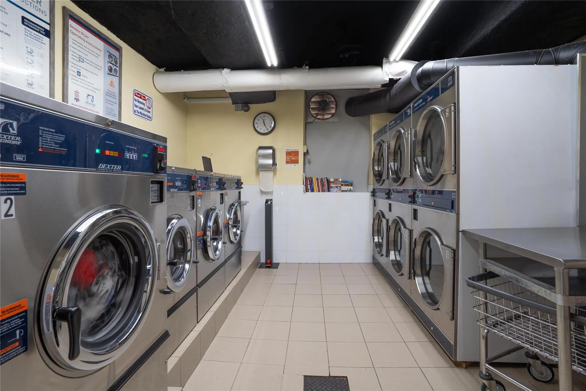 Communal laundry room featuring stacked washer / drying machine, washing machine and dryer, and light tile patterned floors Communal laundry room featuring stacked washer / drying machine, washing machine and dryer, and light tile patterned floors