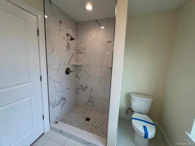 Bathroom featuring a marble finish shower and tile patterned flooring Bathroom featuring a marble finish shower and tile patterned flooring