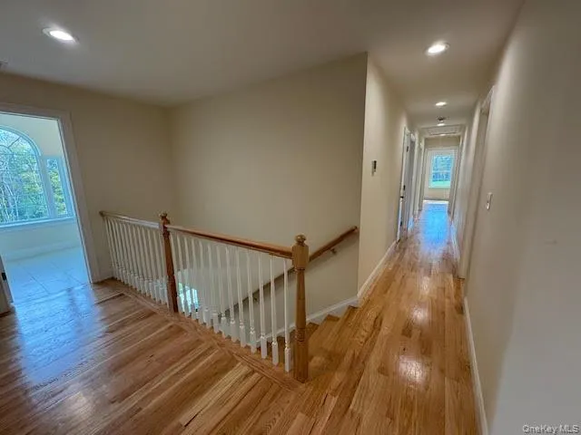Hallway featuring an upstairs landing, recessed lighting, and light wood-style flooring Hallway featuring an upstairs landing, recessed lighting, and light wood-style flooring