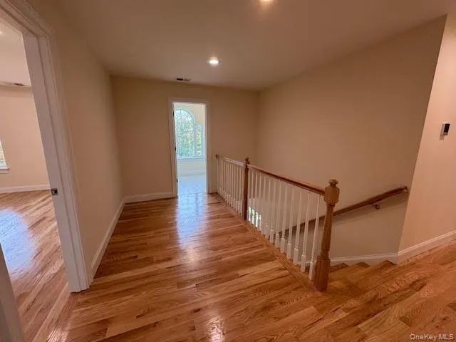 Hallway featuring light wood-type flooring, an upstairs landing, and recessed lighting Hallway featuring light wood-type flooring, an upstairs landing, and recessed lighting