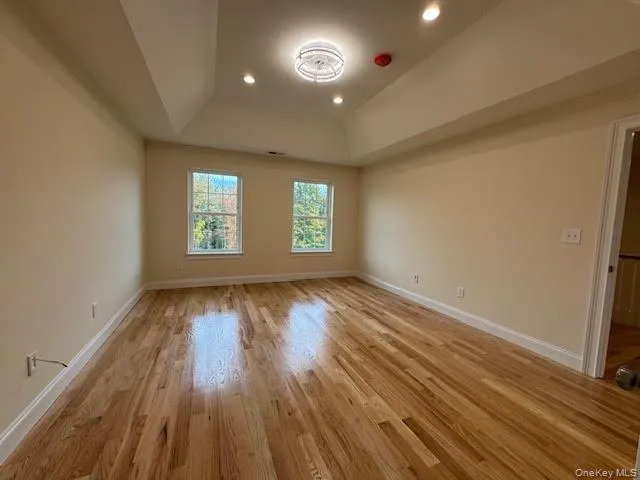 Empty room with recessed lighting, light wood-style floors, and a tray ceiling Empty room with recessed lighting, light wood-style floors, and a tray ceiling