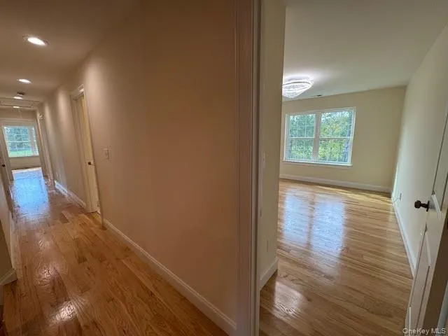 Corridor featuring light wood finished floors and attic access Corridor featuring light wood finished floors and attic access