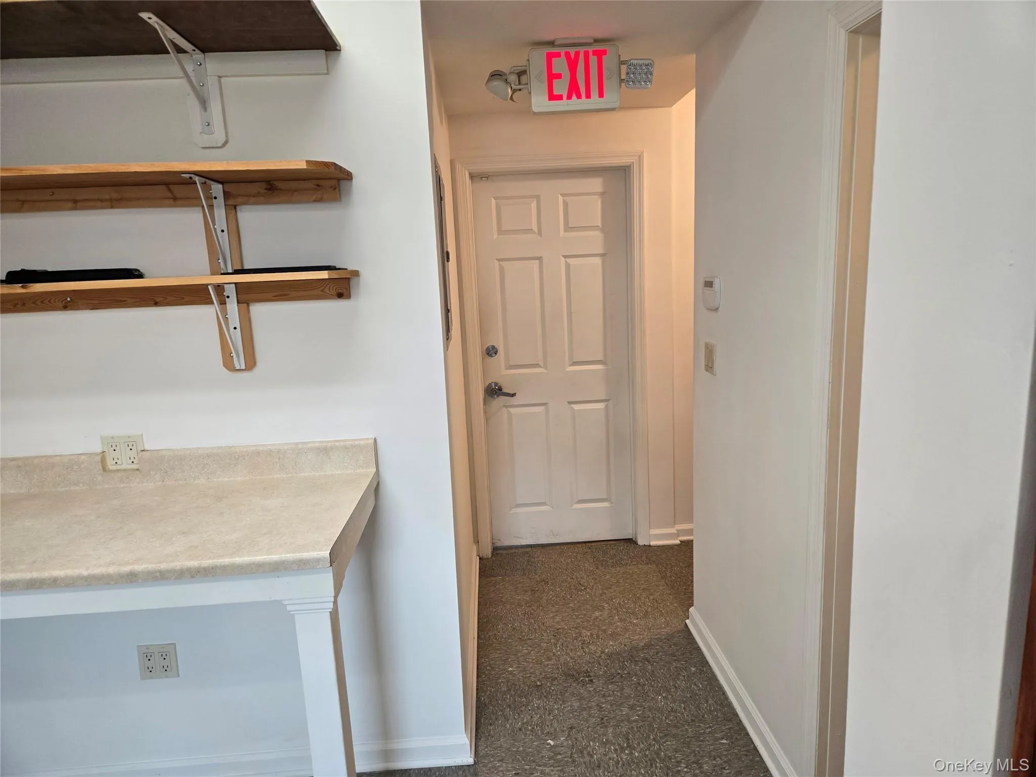 Hallway featuring baseboards and dark colored carpet Hallway featuring baseboards and dark colored carpet
