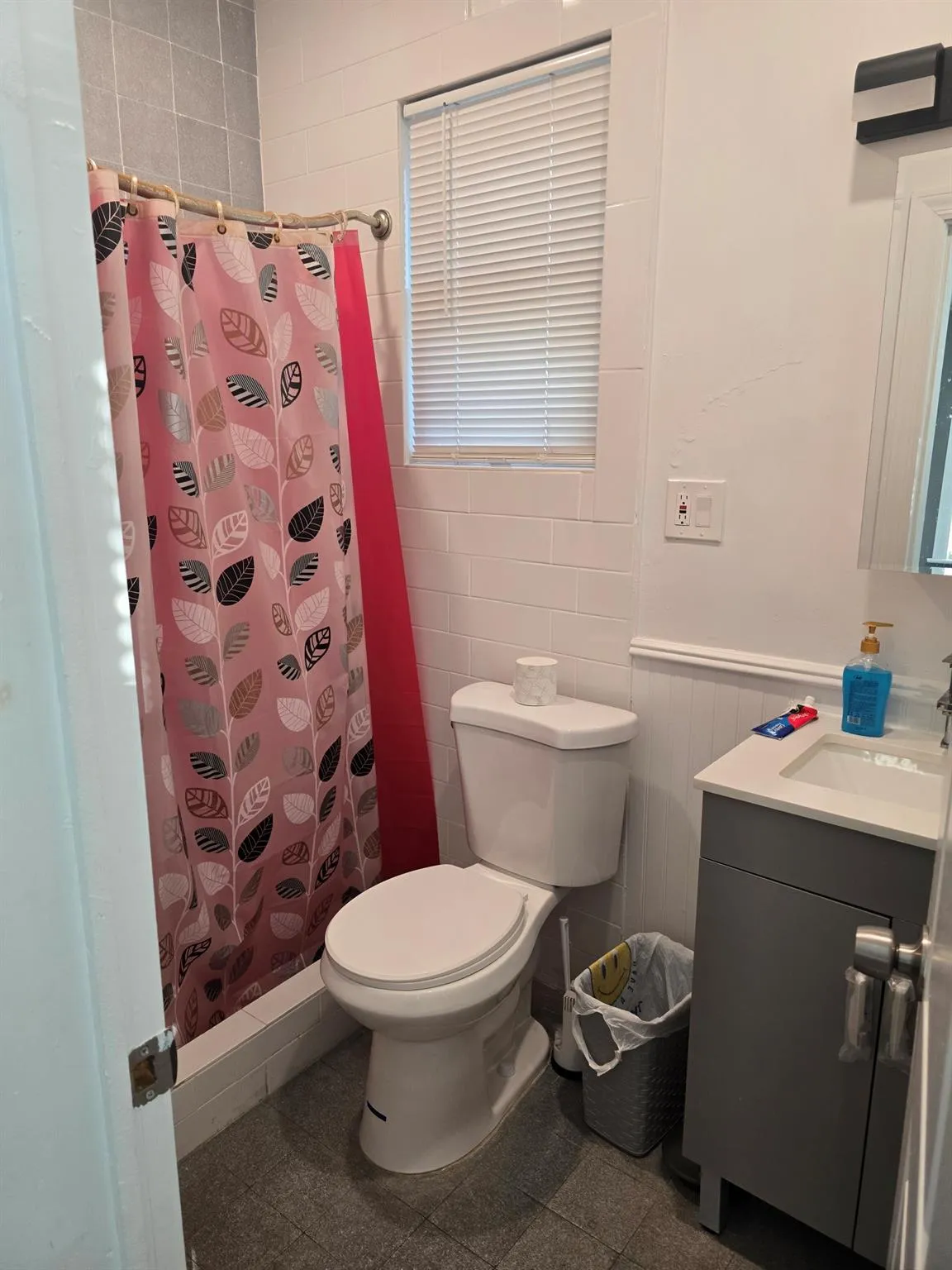 Full bathroom with toilet, vanity, a shower with curtain, and a wainscoted wall Full bathroom with toilet, vanity, a shower with curtain, and a wainscoted wall