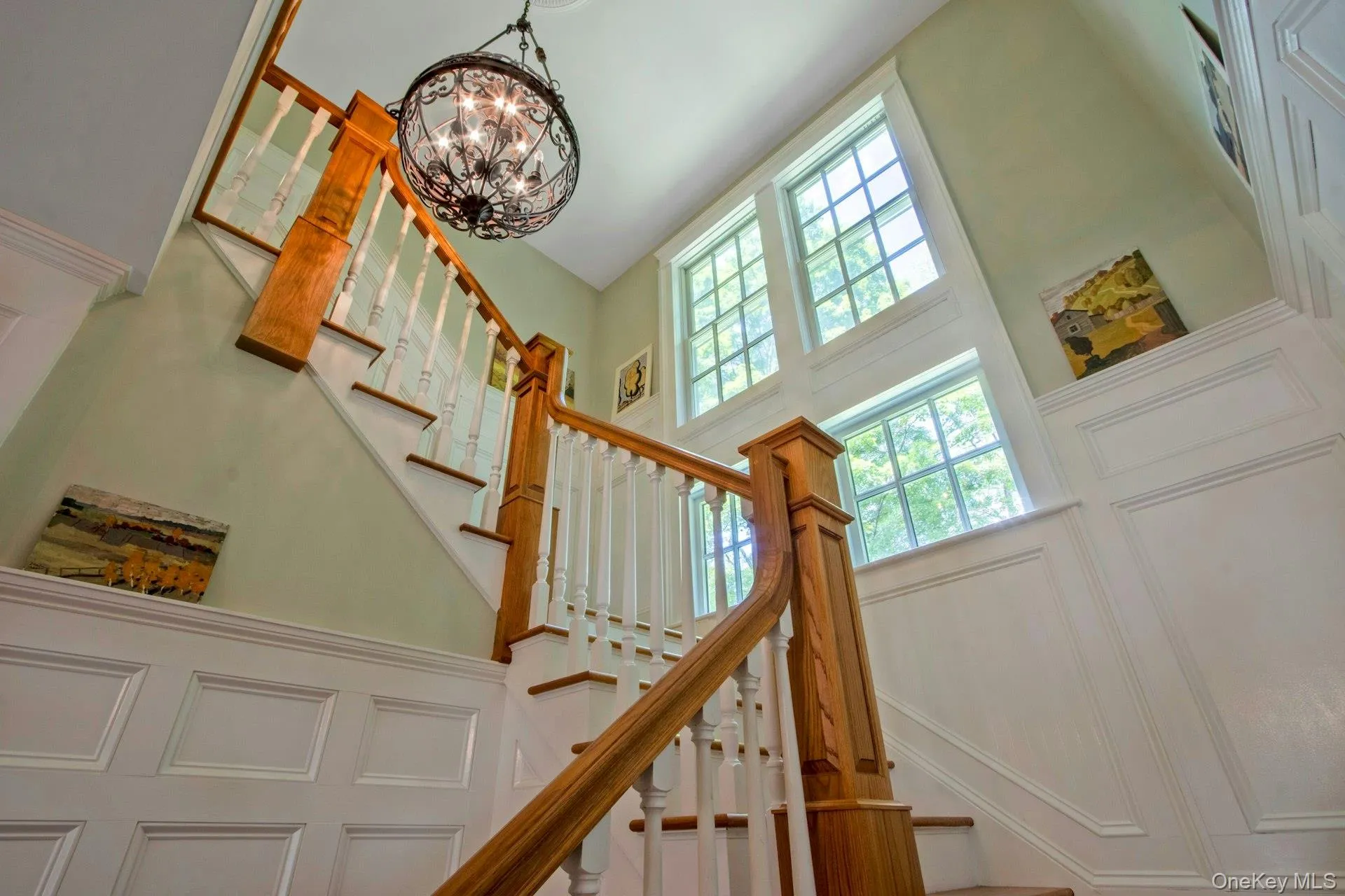Stairs with a towering ceiling, a chandelier, healthy amount of natural light, and a decorative wall Stairs with a towering ceiling, a chandelier, healthy amount of natural light, and a decorative wall