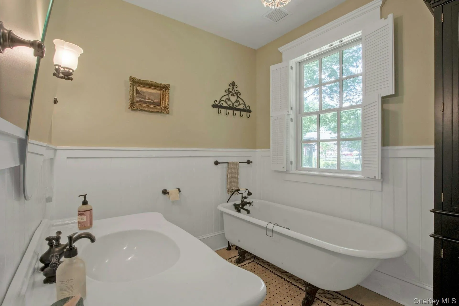 Bathroom featuring a wainscoted wall, a freestanding tub, a sink, and a decorative wall Bathroom featuring a wainscoted wall, a freestanding tub, a sink, and a decorative wall