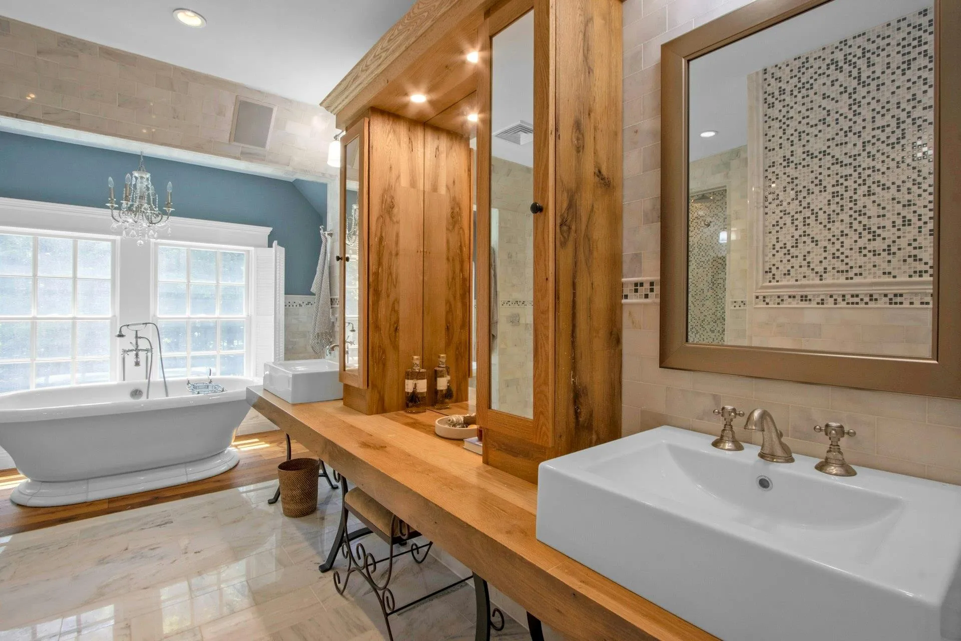 Full bathroom featuring tile walls, a freestanding tub, a sink, and a chandelier Full bathroom featuring tile walls, a freestanding tub, a sink, and a chandelier