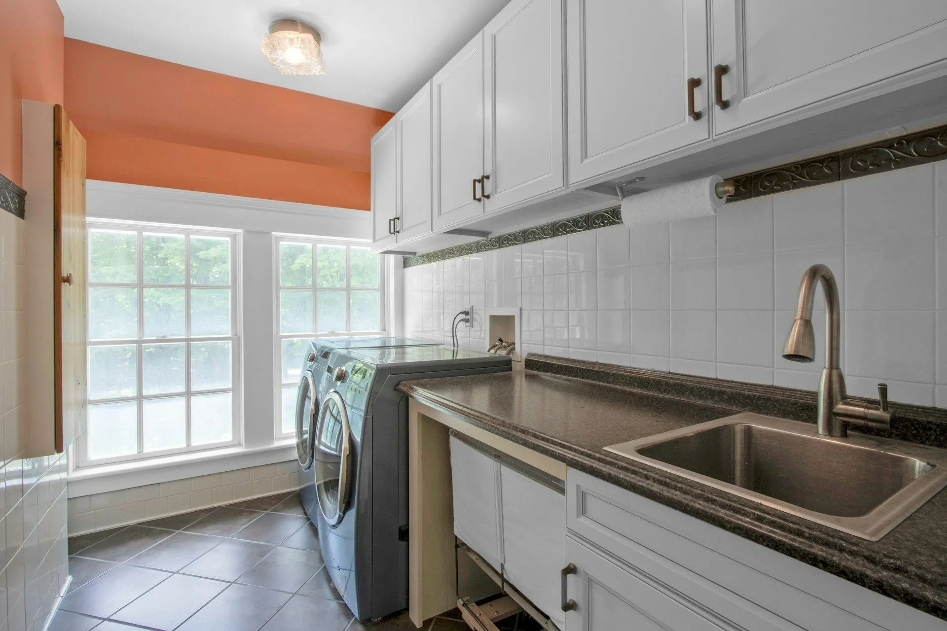 Washroom with washer and dryer, healthy amount of natural light, tile patterned flooring, and cabinet space Washroom with washer and dryer, healthy amount of natural light, tile patterned flooring, and cabinet space