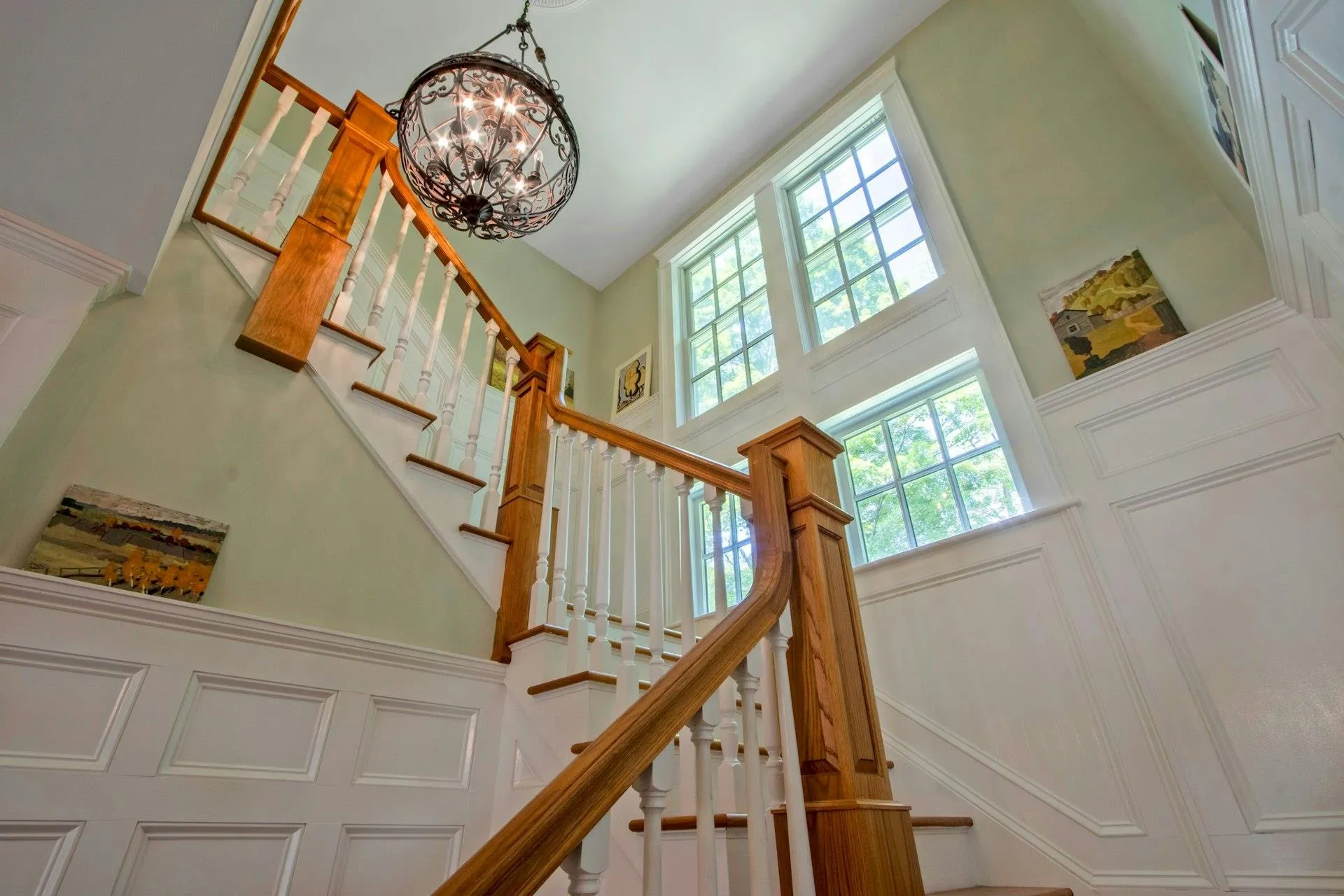 Stairs with a towering ceiling, a chandelier, healthy amount of natural light, and a decorative wall Stairs with a towering ceiling, a chandelier, healthy amount of natural light, and a decorative wall