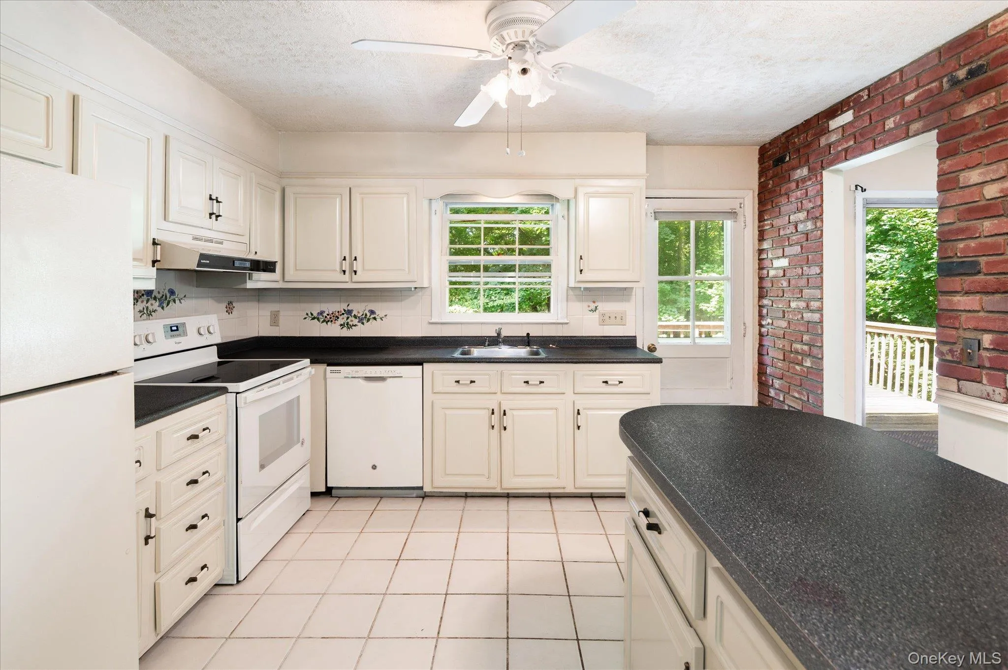 Kitchen Featuring the Brick Accent Wall and Door to the Deck Kitchen Featuring the Brick Accent Wall and Door to the Deck