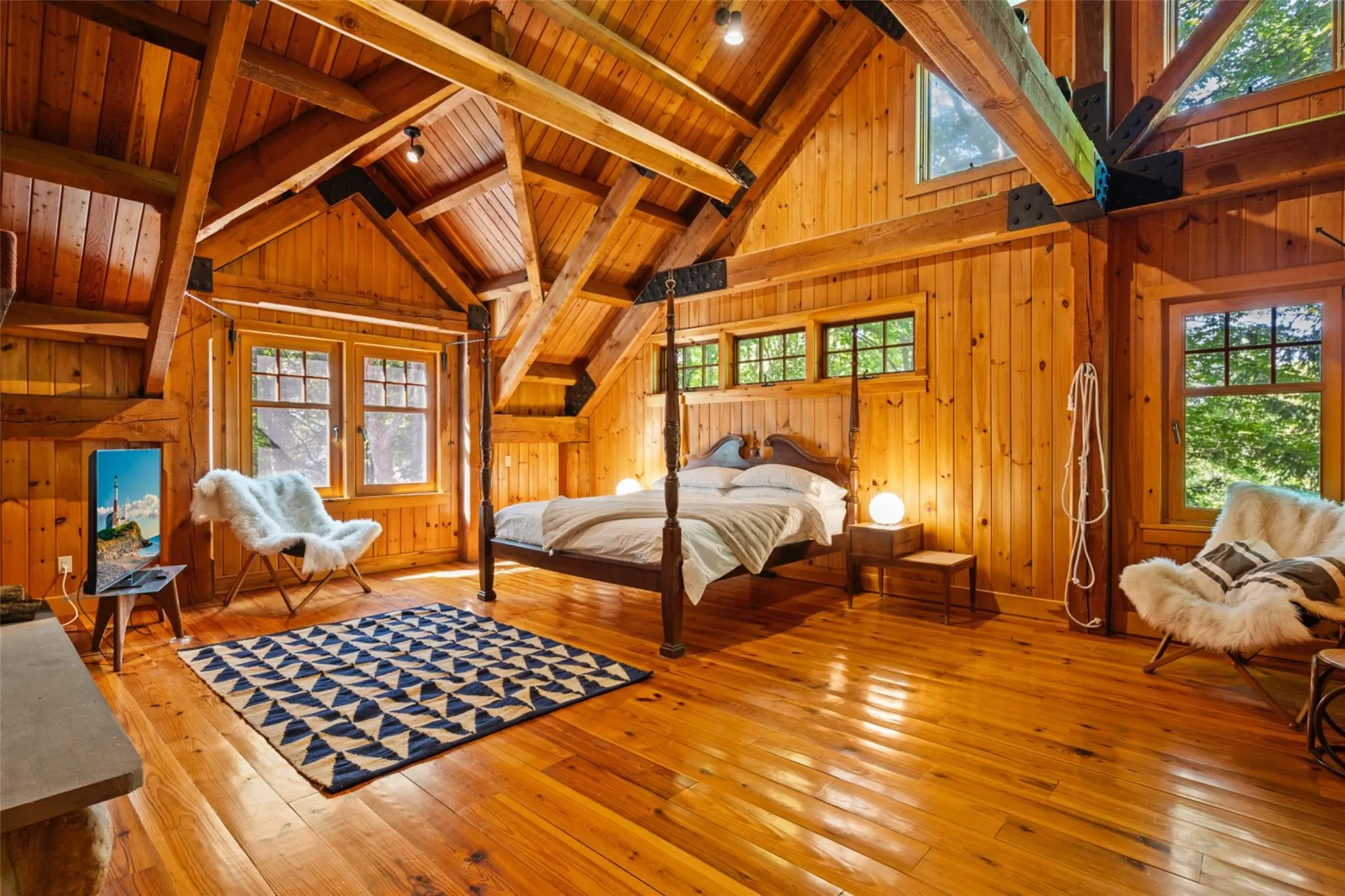 Bedroom with wood ceiling with exposed beams, hardwood / wood-style floors, wood walls, and high vaulted ceiling Bedroom with wood ceiling with exposed beams, hardwood / wood-style floors, wood walls, and high vaulted ceiling