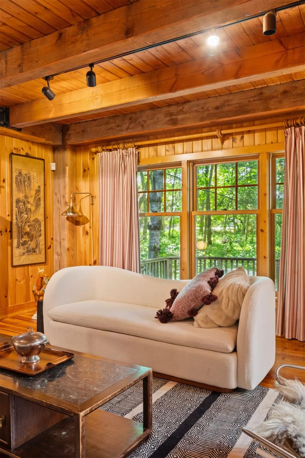 Living area featuring wood ceiling with exposed beams, wooden walls, and wood finished floors Living area featuring wood ceiling with exposed beams, wooden walls, and wood finished floors