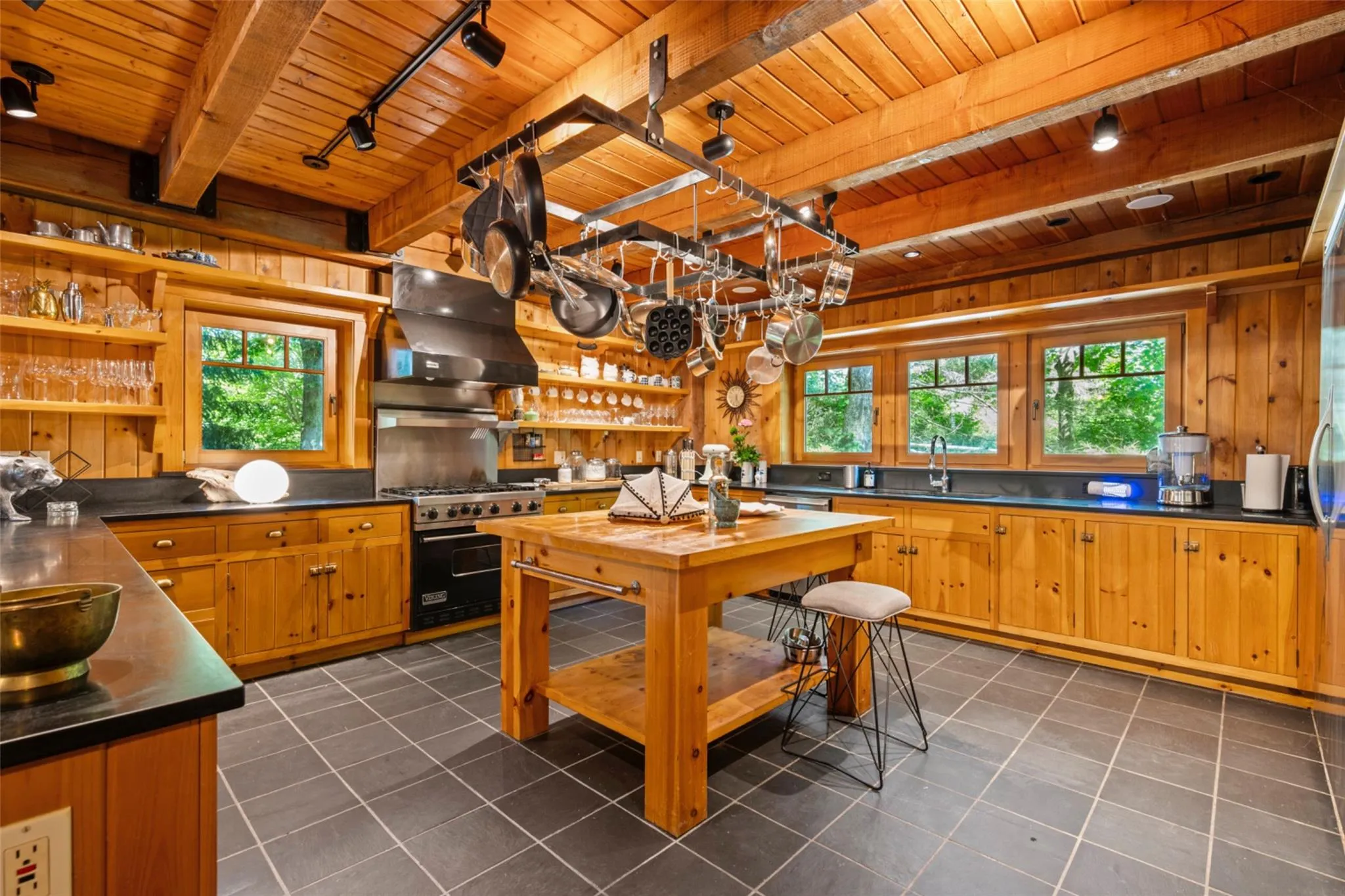 Kitchen with wooden ceiling with exposed beams, premium range, wall chimney exhaust hood, a sink, and track lighting Kitchen with wooden ceiling with exposed beams, premium range, wall chimney exhaust hood, a sink, and track lighting