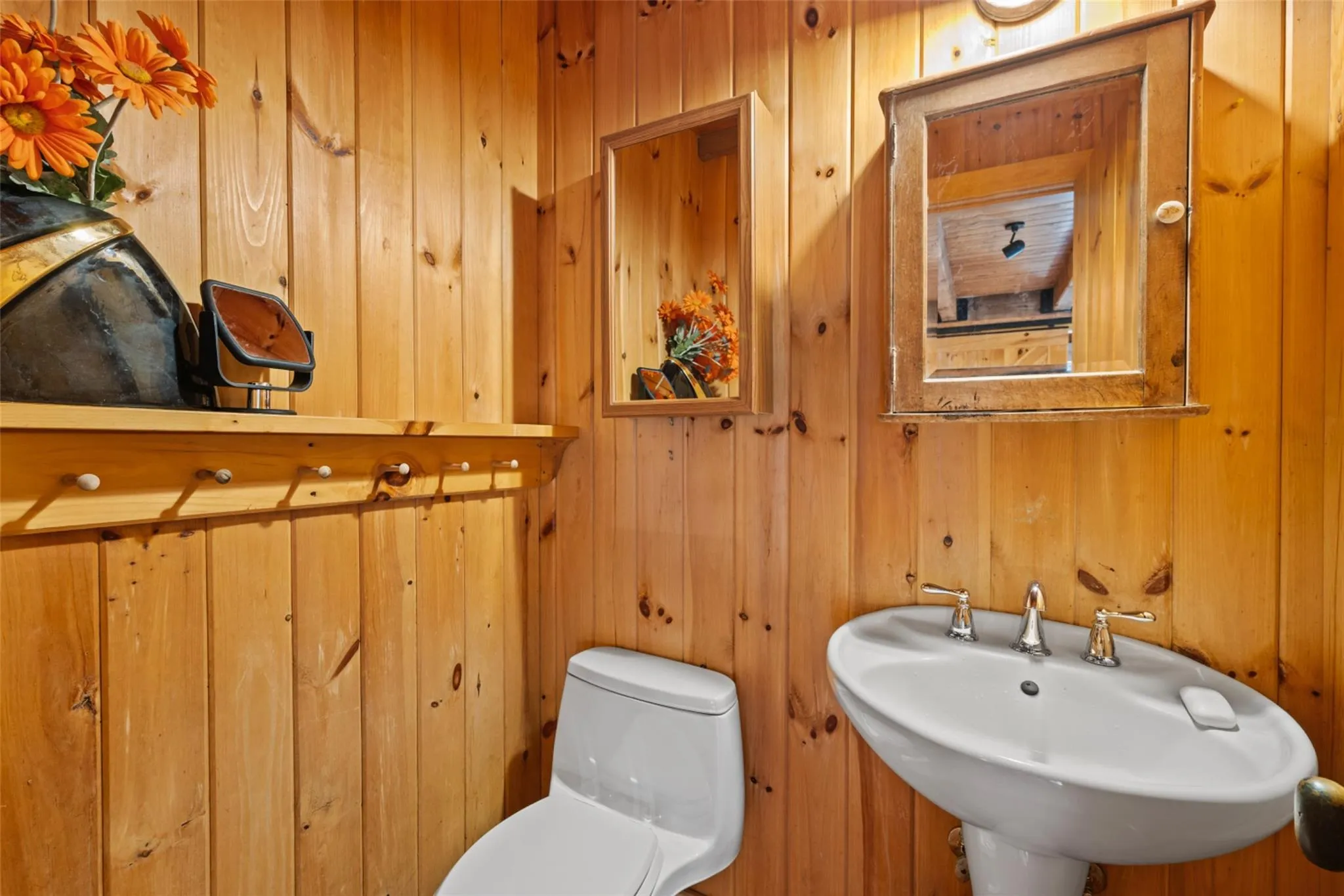 Half bathroom featuring toilet, wooden walls, and a sink Half bathroom featuring toilet, wooden walls, and a sink