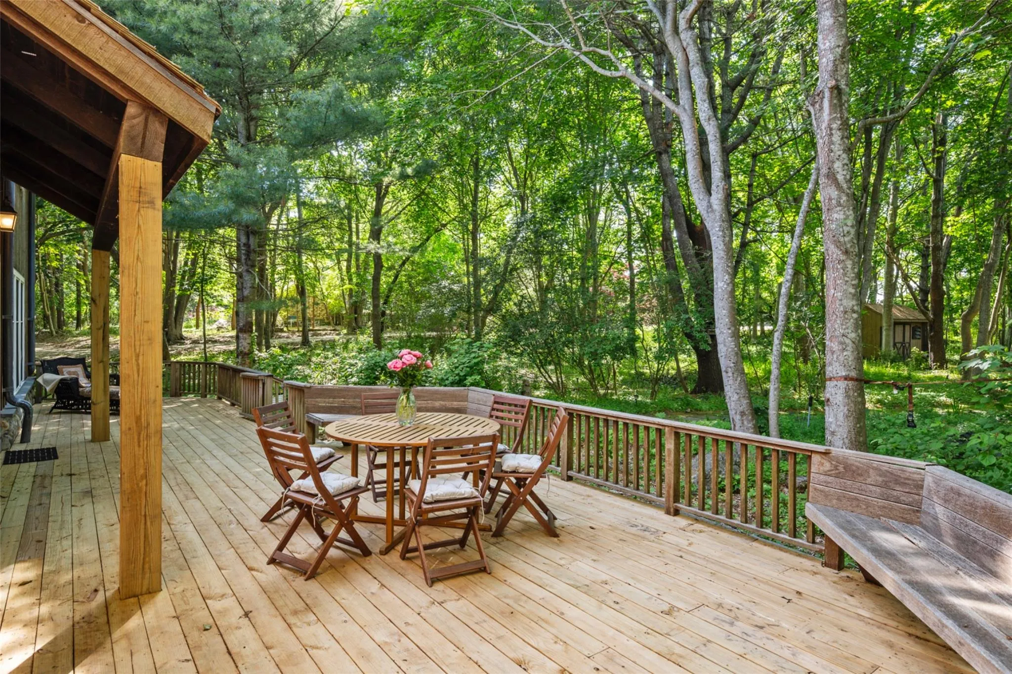 Wooden deck with outdoor dining area and view of wooded area Wooden deck with outdoor dining area and view of wooded area