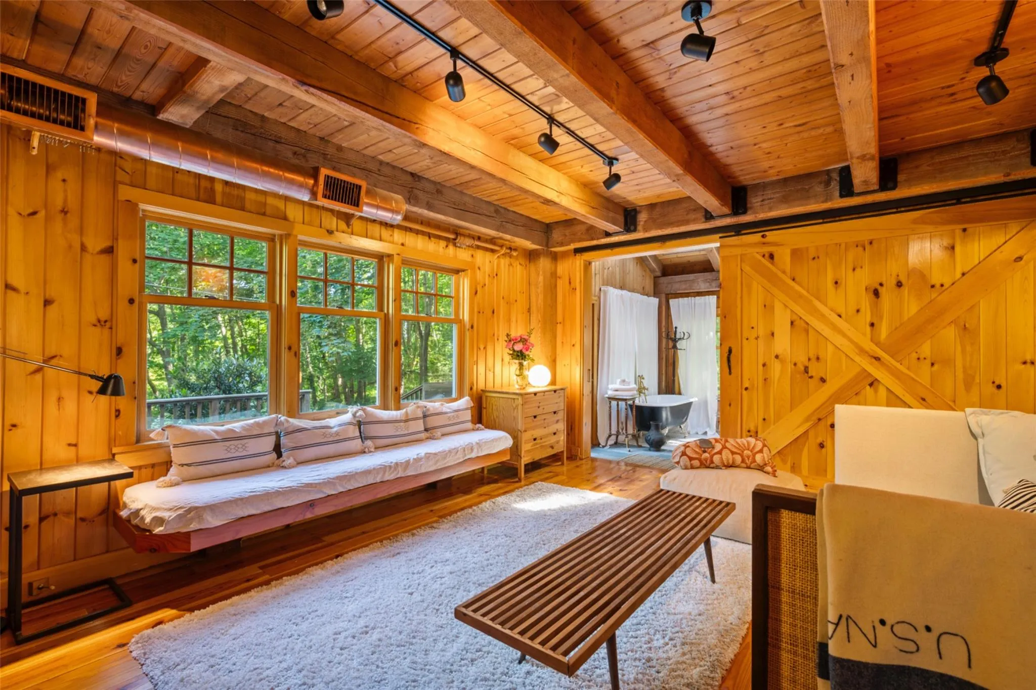 Living area featuring rail lighting, wooden ceiling with exposed beams, wood-type flooring, and wooden walls Living area featuring rail lighting, wooden ceiling with exposed beams, wood-type flooring, and wooden walls