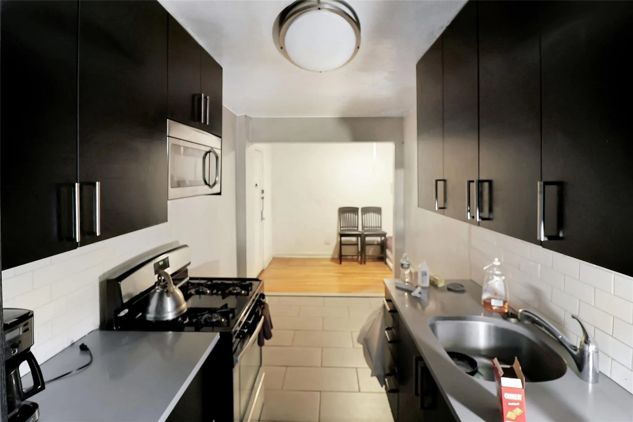 Kitchen with dark cabinetry, stainless steel appliances, tasteful backsplash, and modern cabinets Kitchen with dark cabinetry, stainless steel appliances, tasteful backsplash, and modern cabinets