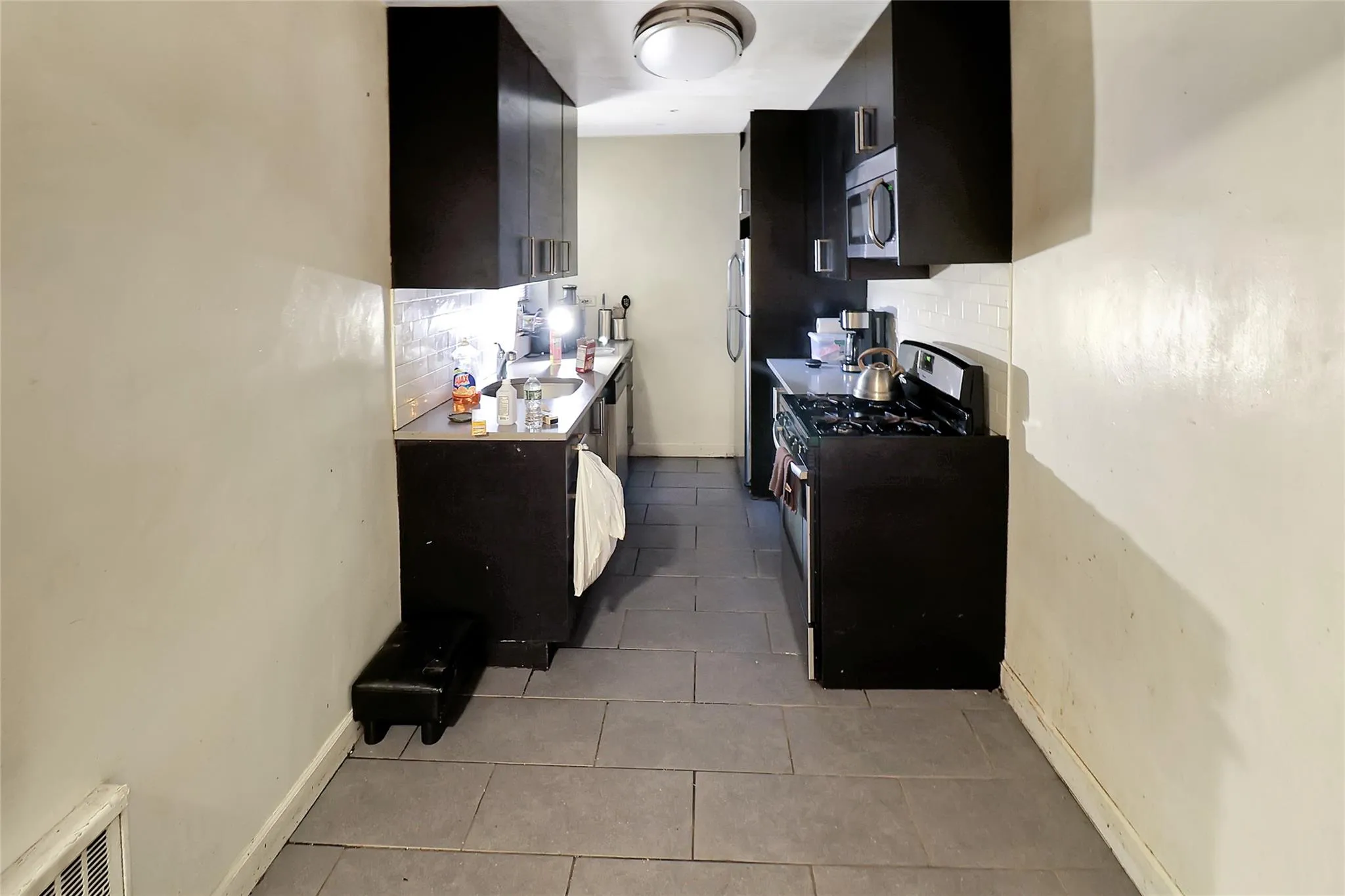 Kitchen with range with gas cooktop, stainless steel microwave, dark cabinets, and backsplash Kitchen with range with gas cooktop, stainless steel microwave, dark cabinets, and backsplash