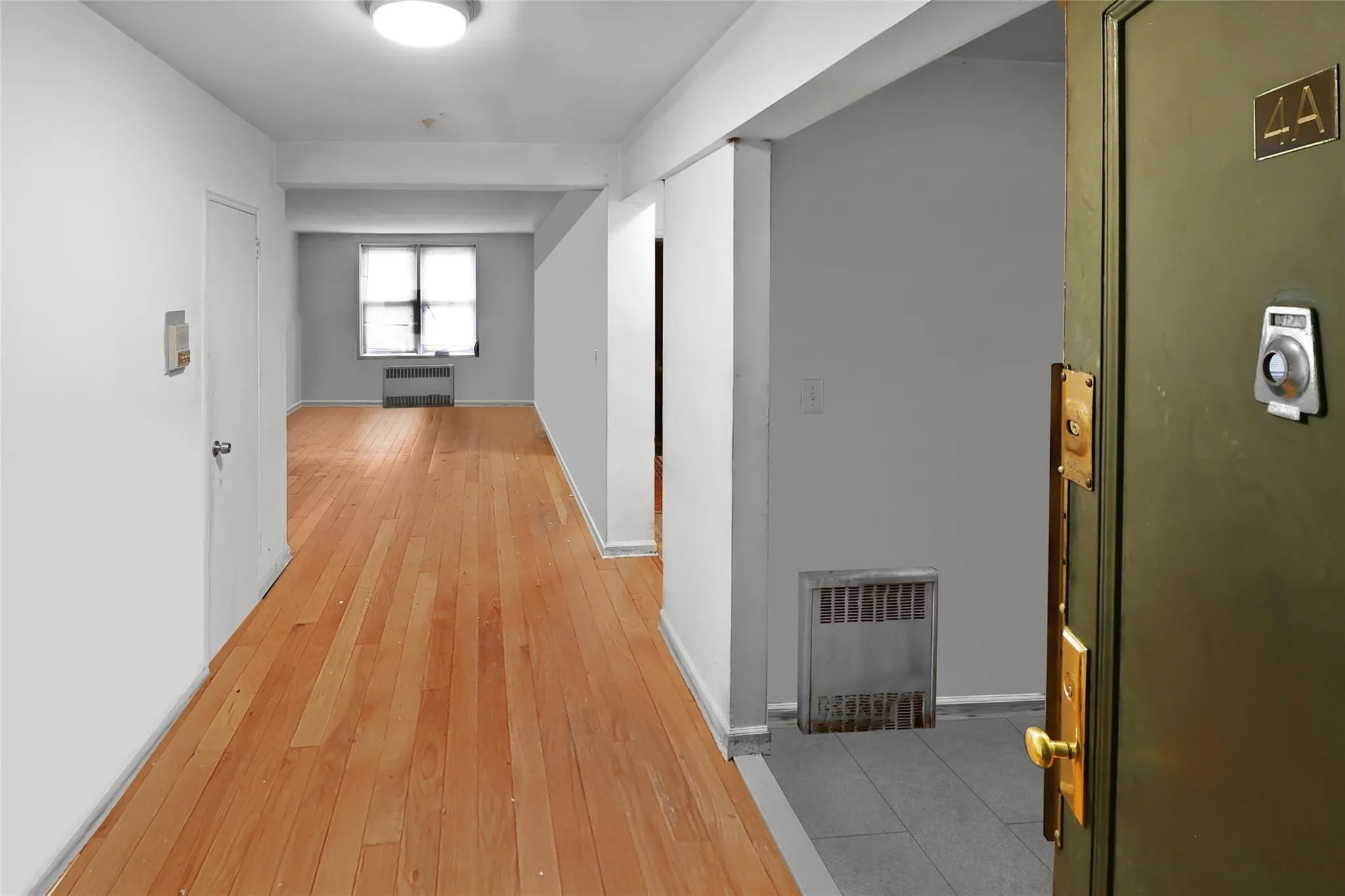 Hallway featuring light wood finished floors, baseboards, heating unit, and a wall unit AC Hallway featuring light wood finished floors, baseboards, heating unit, and a wall unit AC