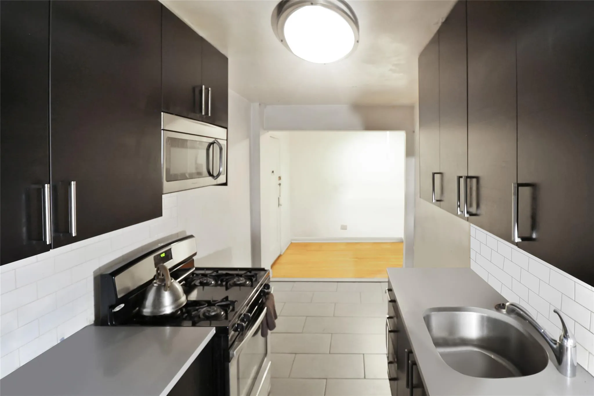 Kitchen with appliances with stainless steel finishes, a sink, backsplash, and dark cabinetry Kitchen with appliances with stainless steel finishes, a sink, backsplash, and dark cabinetry