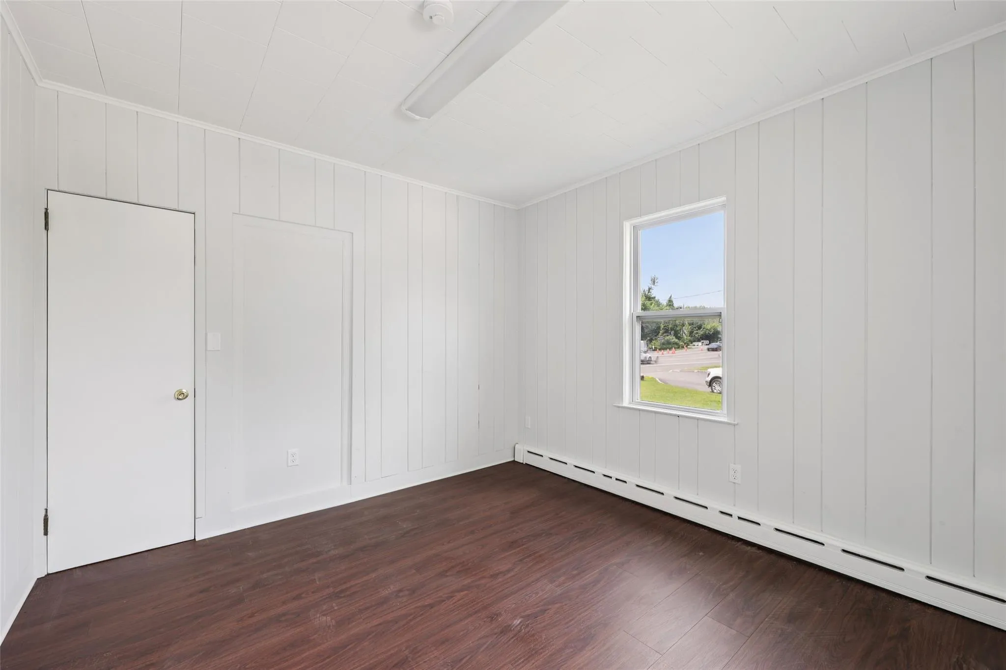 Unfurnished room with a baseboard heating unit, dark wood finished floors, crown molding, and a smoke detector Unfurnished room with a baseboard heating unit, dark wood finished floors, crown molding, and a smoke detector