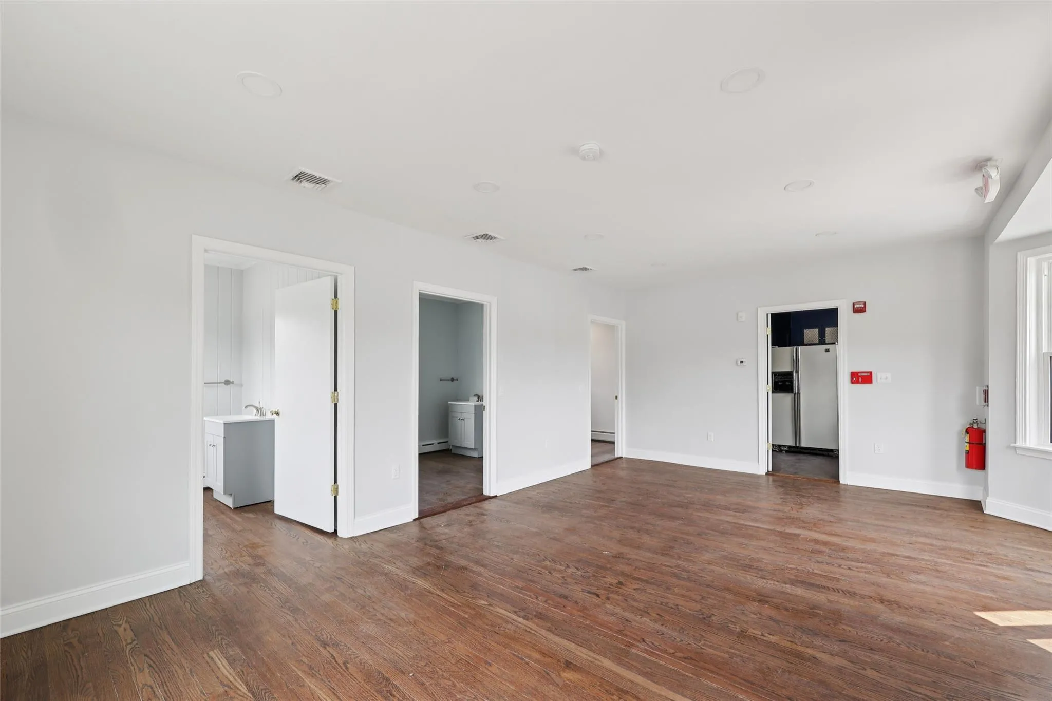 Unfurnished room with dark wood-type flooring, a smoke detector, and a baseboard heating unit Unfurnished room with dark wood-type flooring, a smoke detector, and a baseboard heating unit