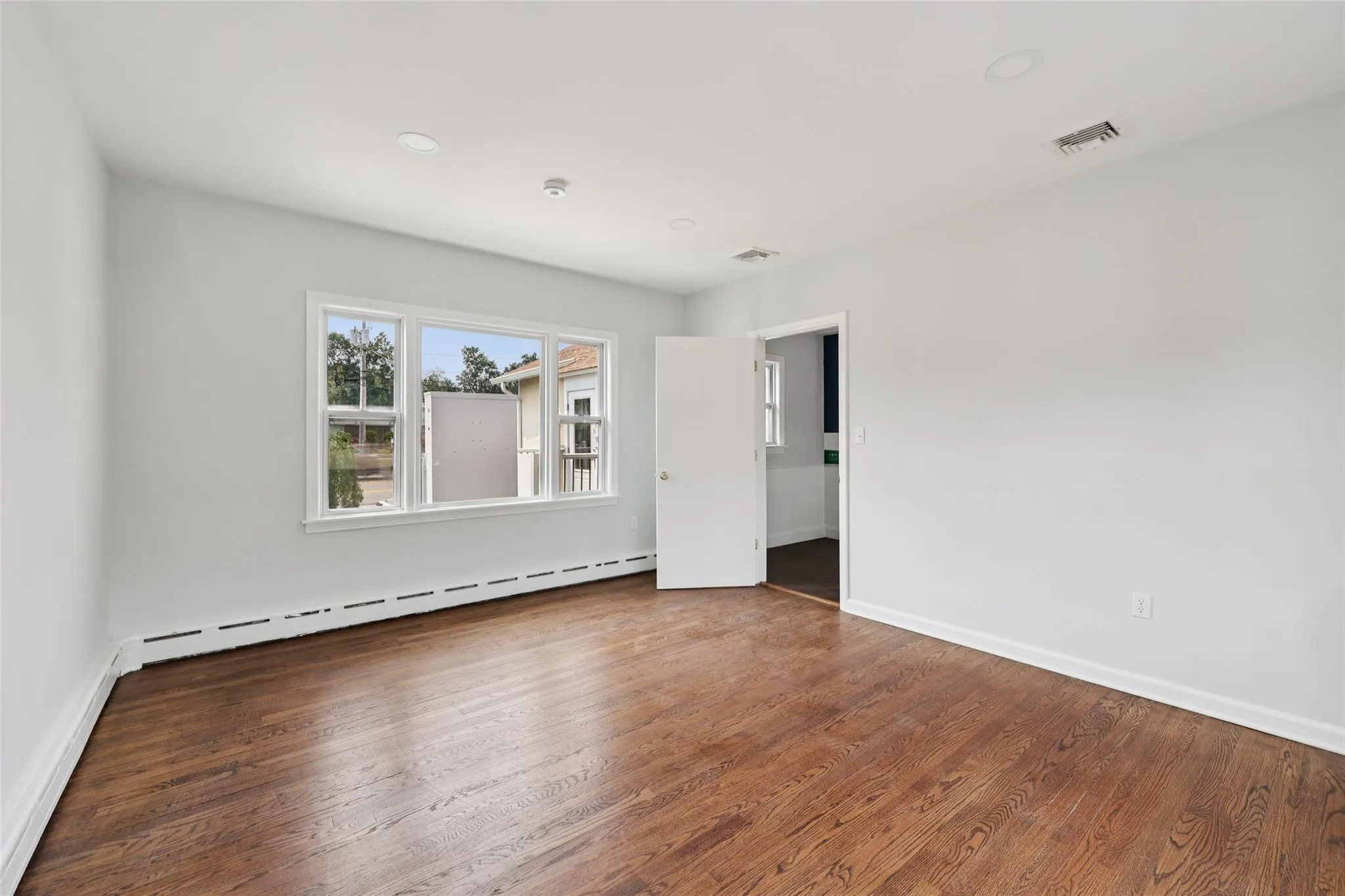 Empty room featuring a baseboard heating unit, wood finished floors, and recessed lighting Empty room featuring a baseboard heating unit, wood finished floors, and recessed lighting
