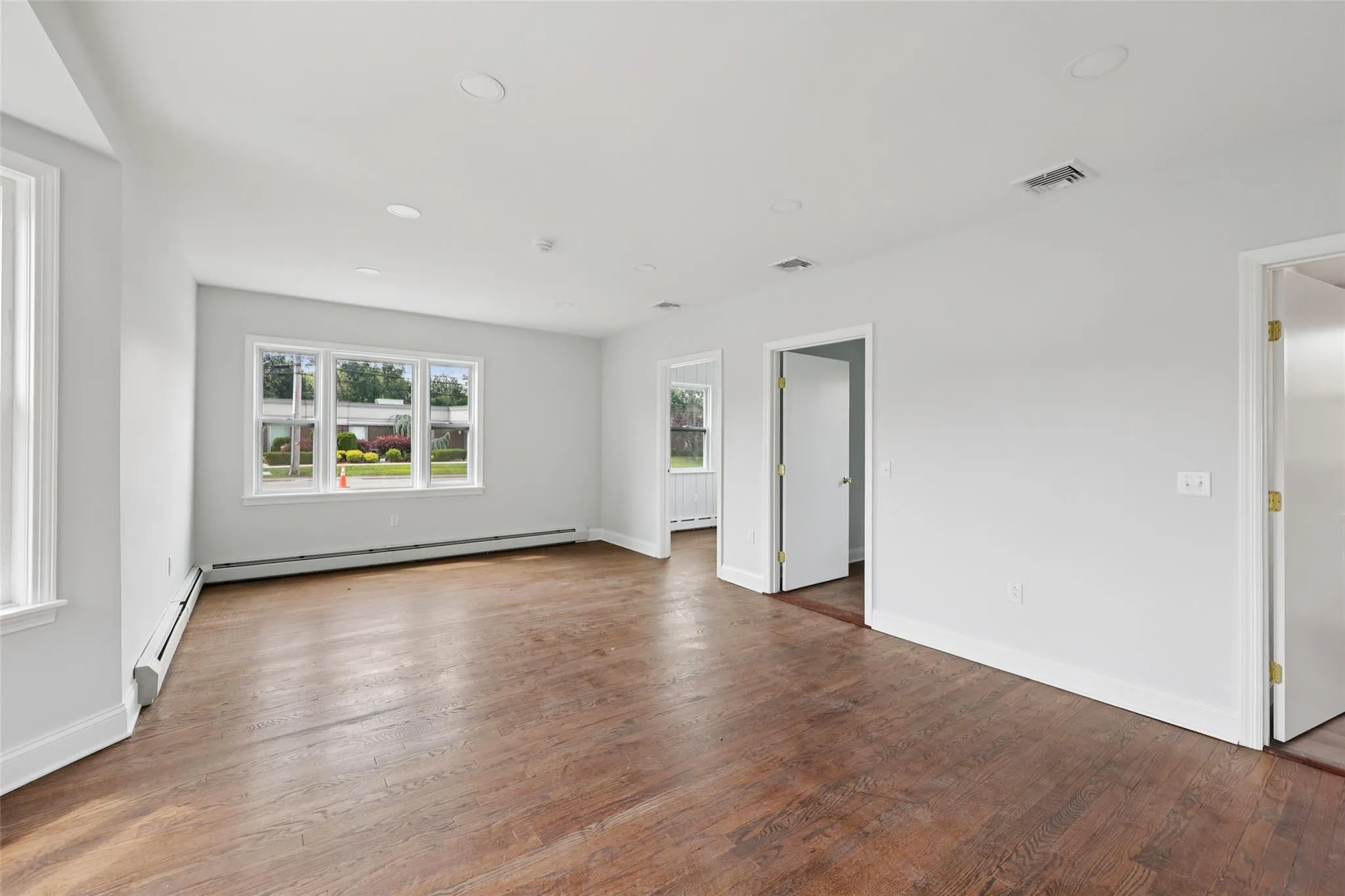 Spare room with baseboard heating, wood finished floors, and recessed lighting Spare room with baseboard heating, wood finished floors, and recessed lighting