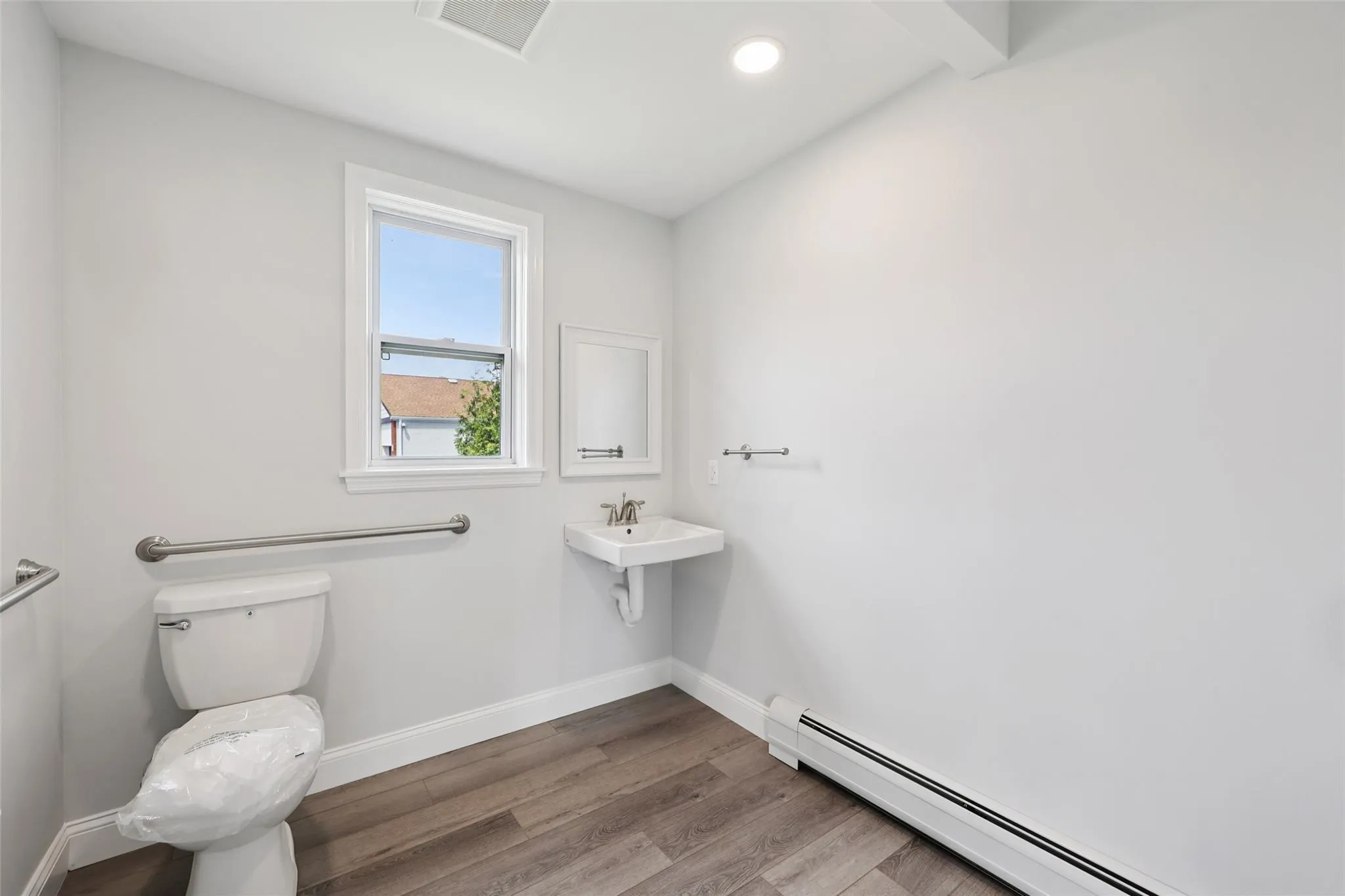 Half bath featuring a baseboard radiator, wood finished floors, and recessed lighting Half bath featuring a baseboard radiator, wood finished floors, and recessed lighting