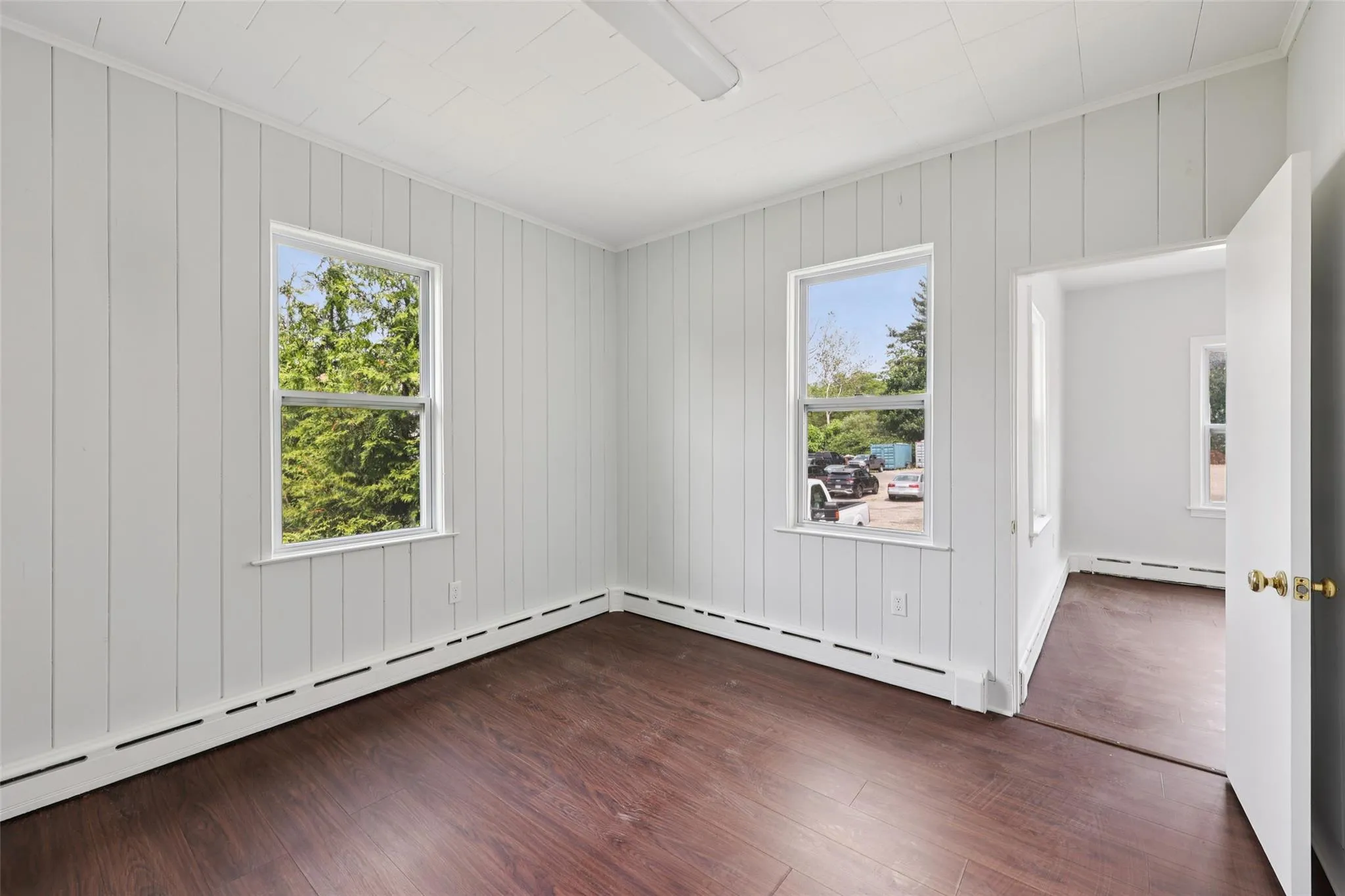 Empty room featuring baseboard heating and dark wood-style floors Empty room featuring baseboard heating and dark wood-style floors