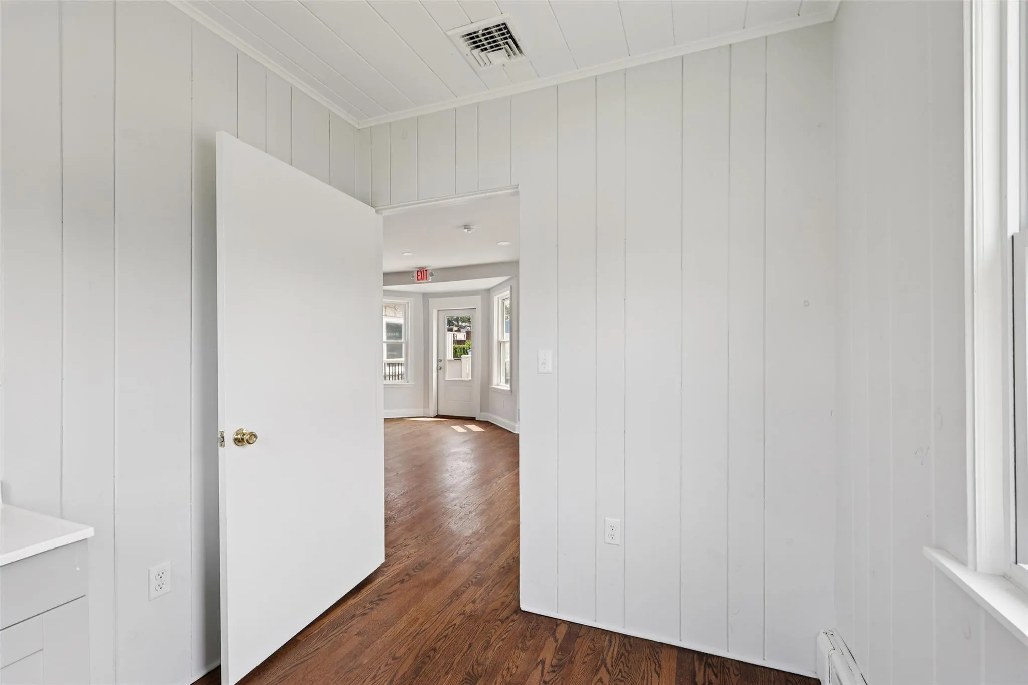 Corridor with ornamental molding, dark wood-style floors, and a baseboard radiator Corridor with ornamental molding, dark wood-style floors, and a baseboard radiator