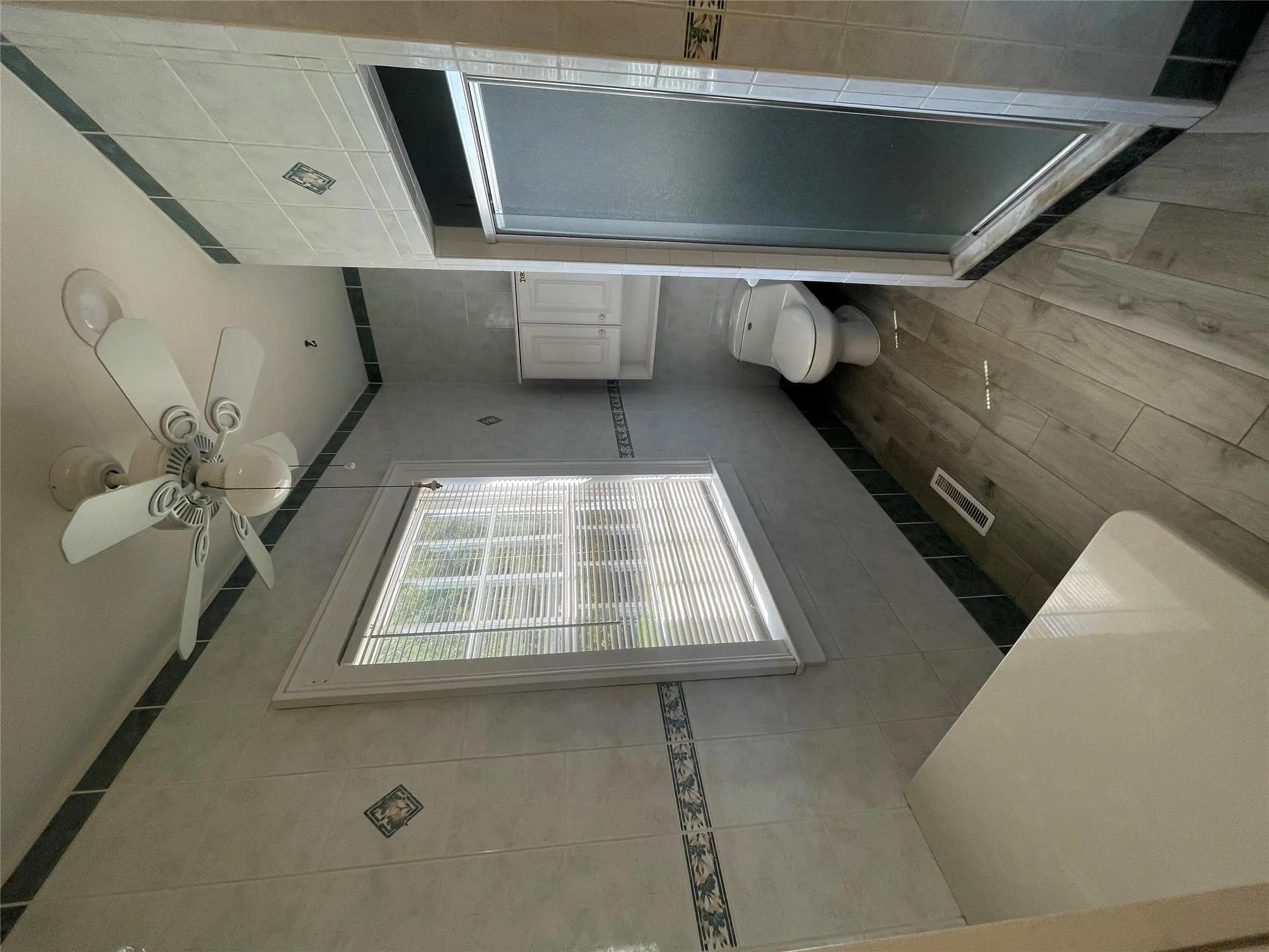 Full bathroom with tile walls, a shower stall, a ceiling fan, and wood finished floors Full bathroom with tile walls, a shower stall, a ceiling fan, and wood finished floors