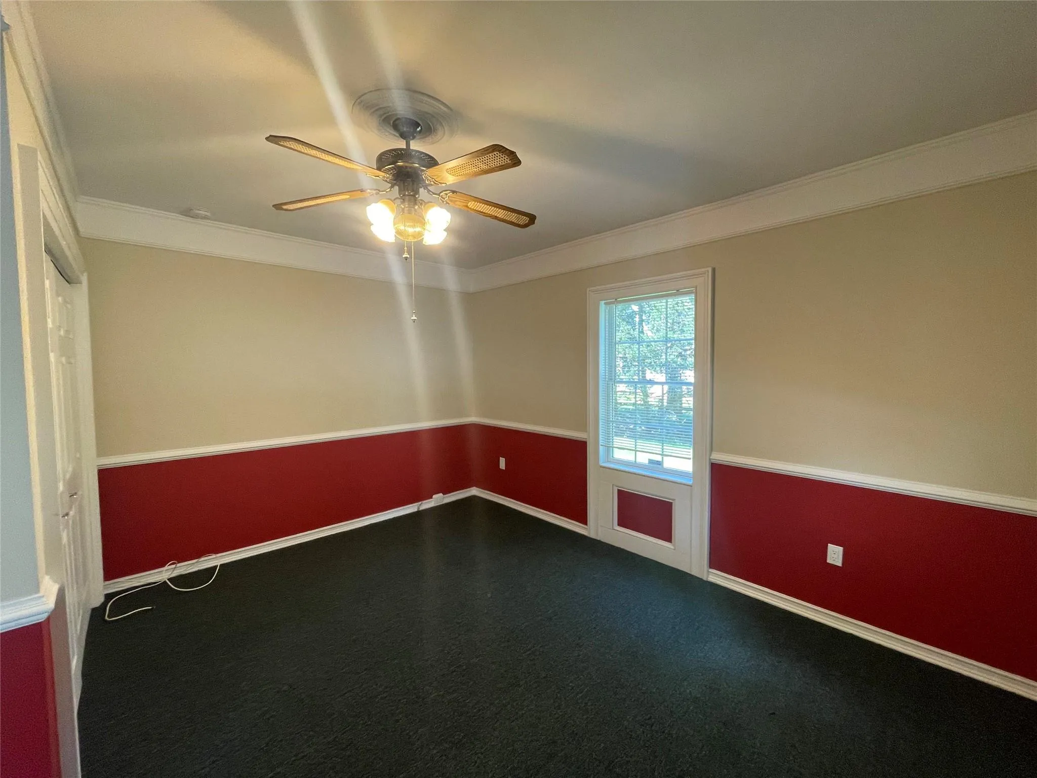 Spare room with ceiling fan, crown molding, and dark carpet Spare room with ceiling fan, crown molding, and dark carpet