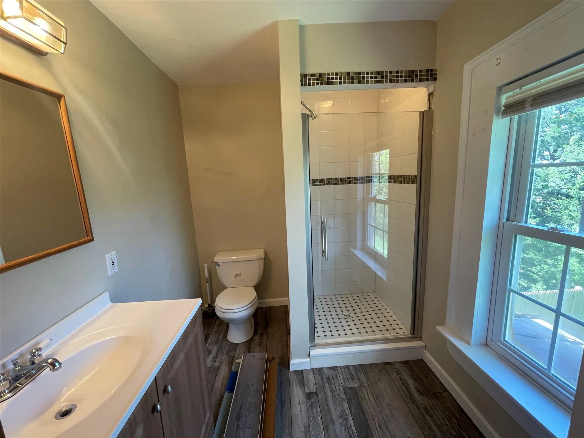 Bathroom featuring wood finished floors, vanity, a stall shower, and a wall mounted AC Bathroom featuring wood finished floors, vanity, a stall shower, and a wall mounted AC