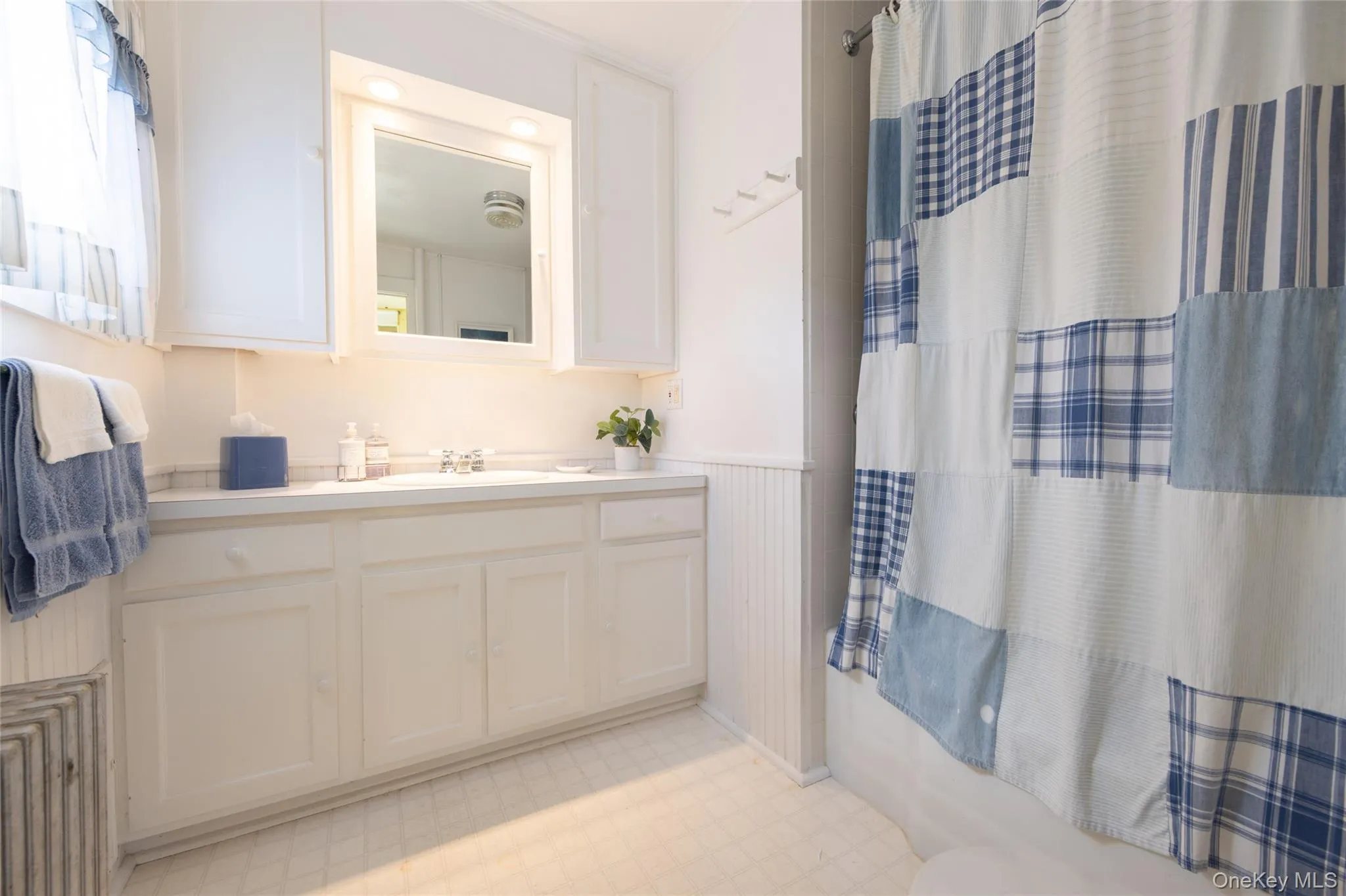 Bathroom featuring vanity, tile patterned floors, a wainscoted wall, shower / bath combo, and toilet Bathroom featuring vanity, tile patterned floors, a wainscoted wall, shower / bath combo, and toilet