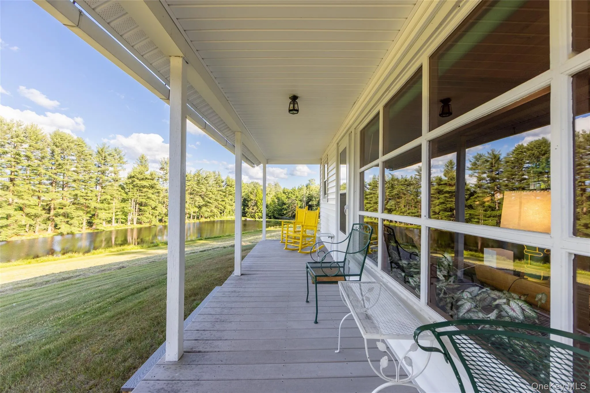 Wooden porch featuring a water view, a yard, and view of wooded area Wooden porch featuring a water view, a yard, and view of wooded area
