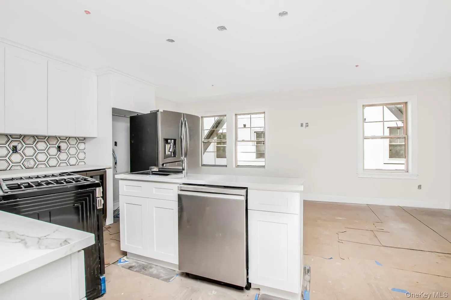 Kitchen featuring appliances with stainless steel finishes, light countertops, white cabinetry, and decorative backsplash Kitchen featuring appliances with stainless steel finishes, light countertops, white cabinetry, and decorative backsplash