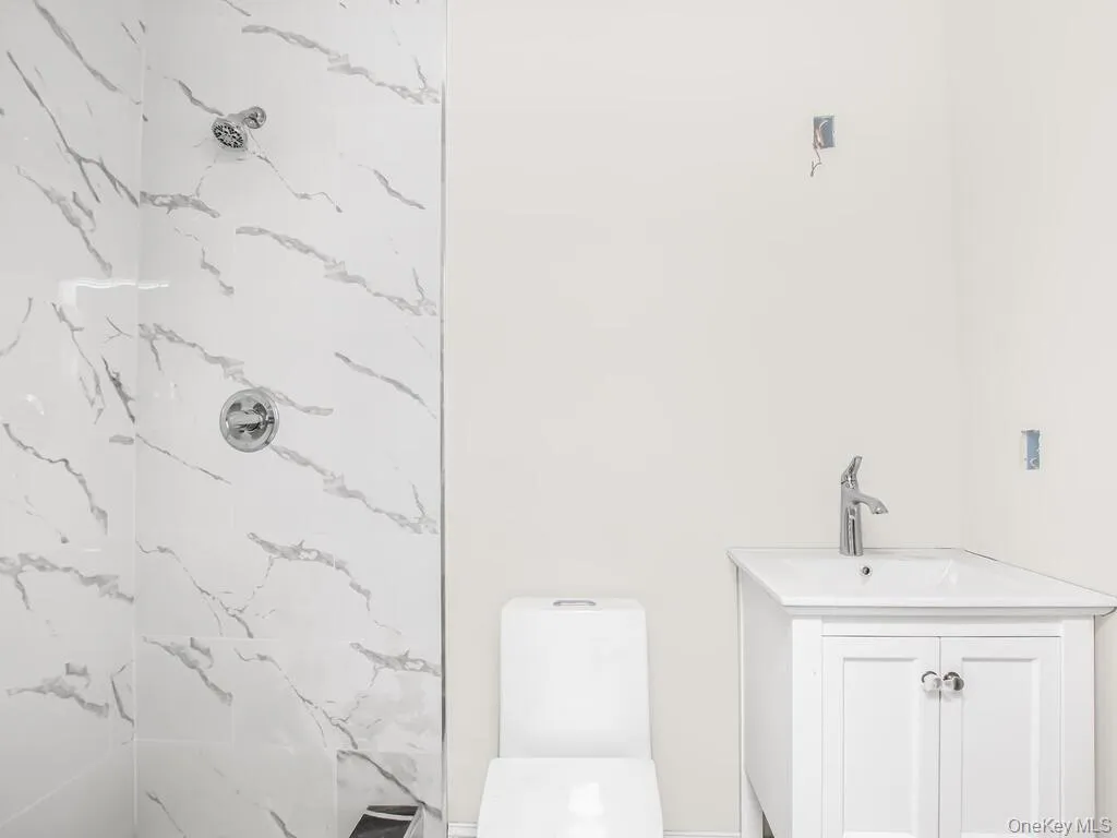 Full bathroom with a marble finish shower, vanity, and toilet Full bathroom with a marble finish shower, vanity, and toilet