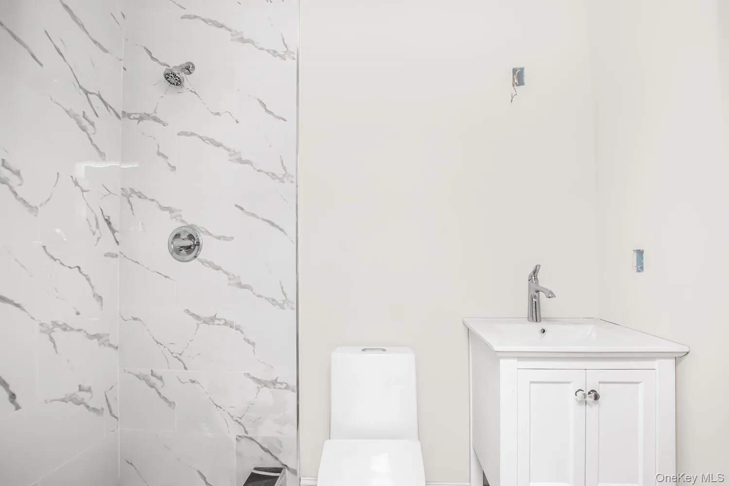 Bathroom featuring a marble finish shower, vanity, and toilet Bathroom featuring a marble finish shower, vanity, and toilet