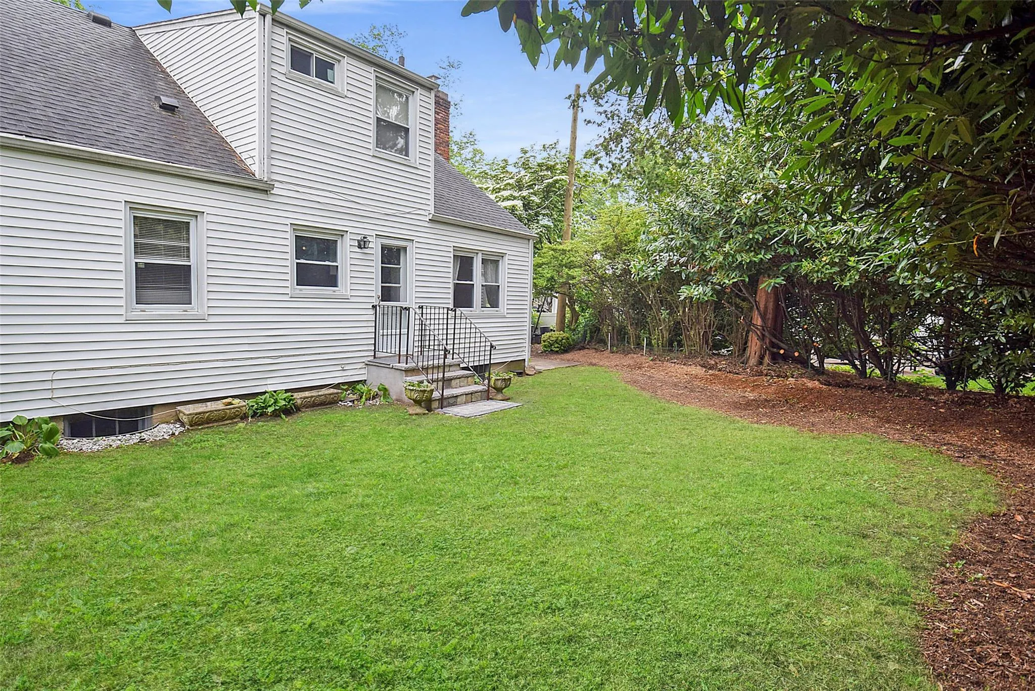 Rear view of house with roof with shingles and a lawn Rear view of house with roof with shingles and a lawn