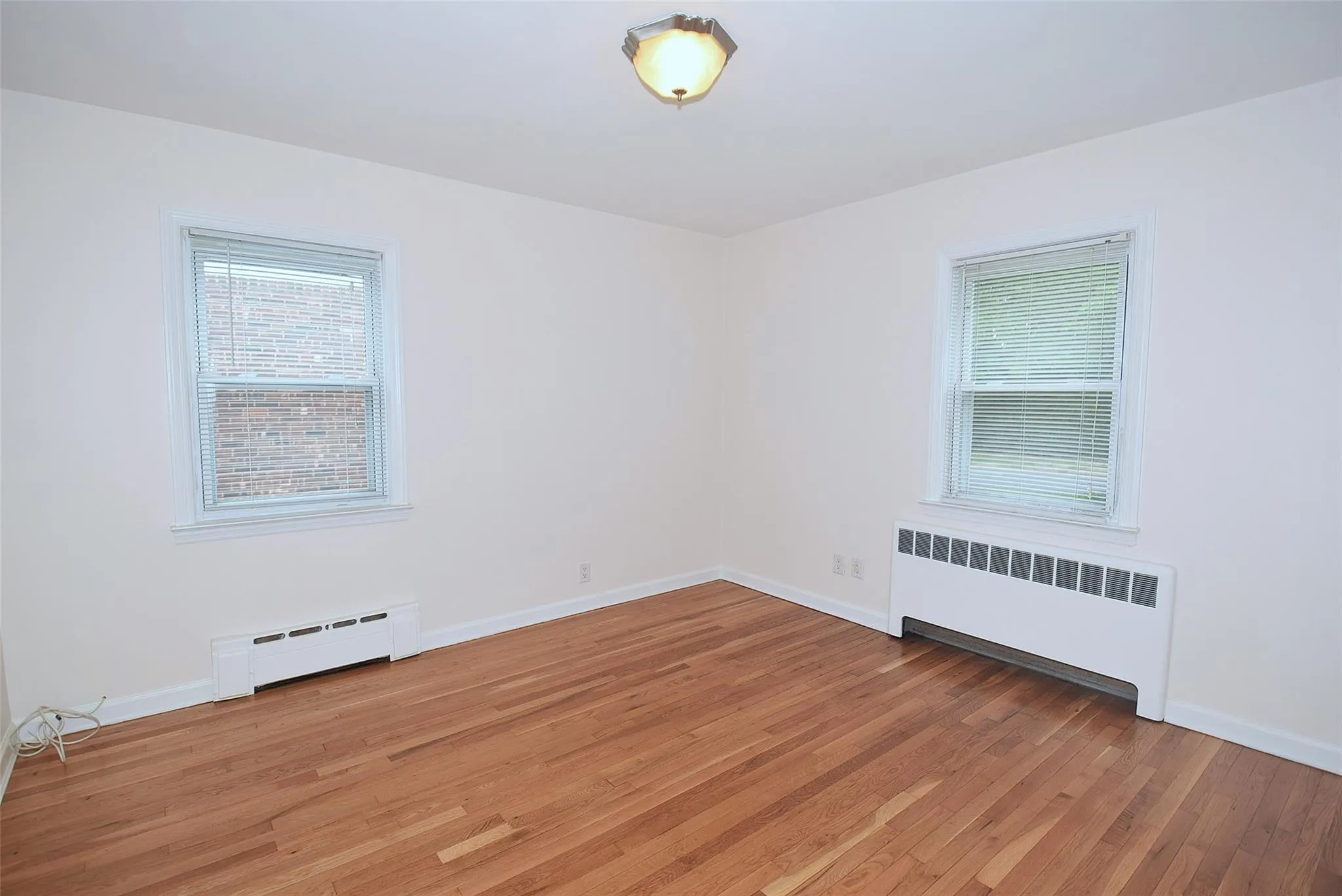 Spare room featuring radiator, baseboard heating, healthy amount of natural light, and light wood-type flooring Spare room featuring radiator, baseboard heating, healthy amount of natural light, and light wood-type flooring