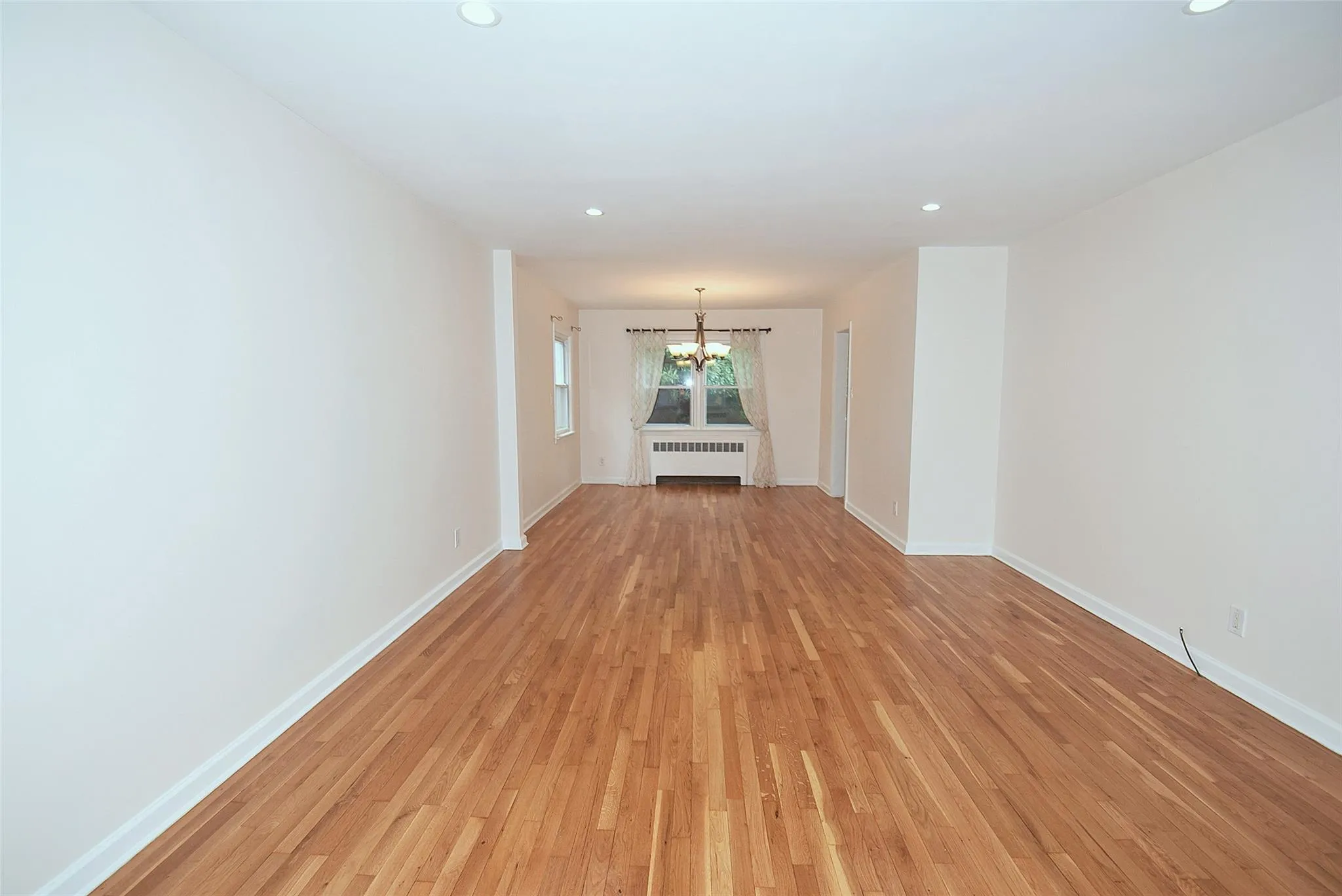 Living Rm, dining room with radiator heating unit, a chandelier, recessed lighting, light wood-style floors, and baseboards Living Rm, dining room with radiator heating unit, a chandelier, recessed lighting, light wood-style floors, and baseboards