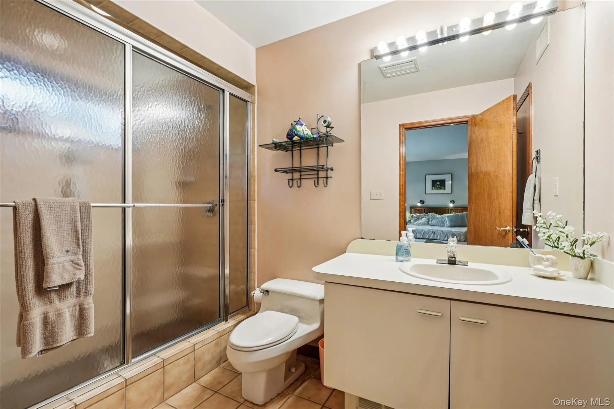 Ensuite bathroom with vanity, tile patterned flooring, and a shower with shower door Ensuite bathroom with vanity, tile patterned flooring, and a shower with shower door