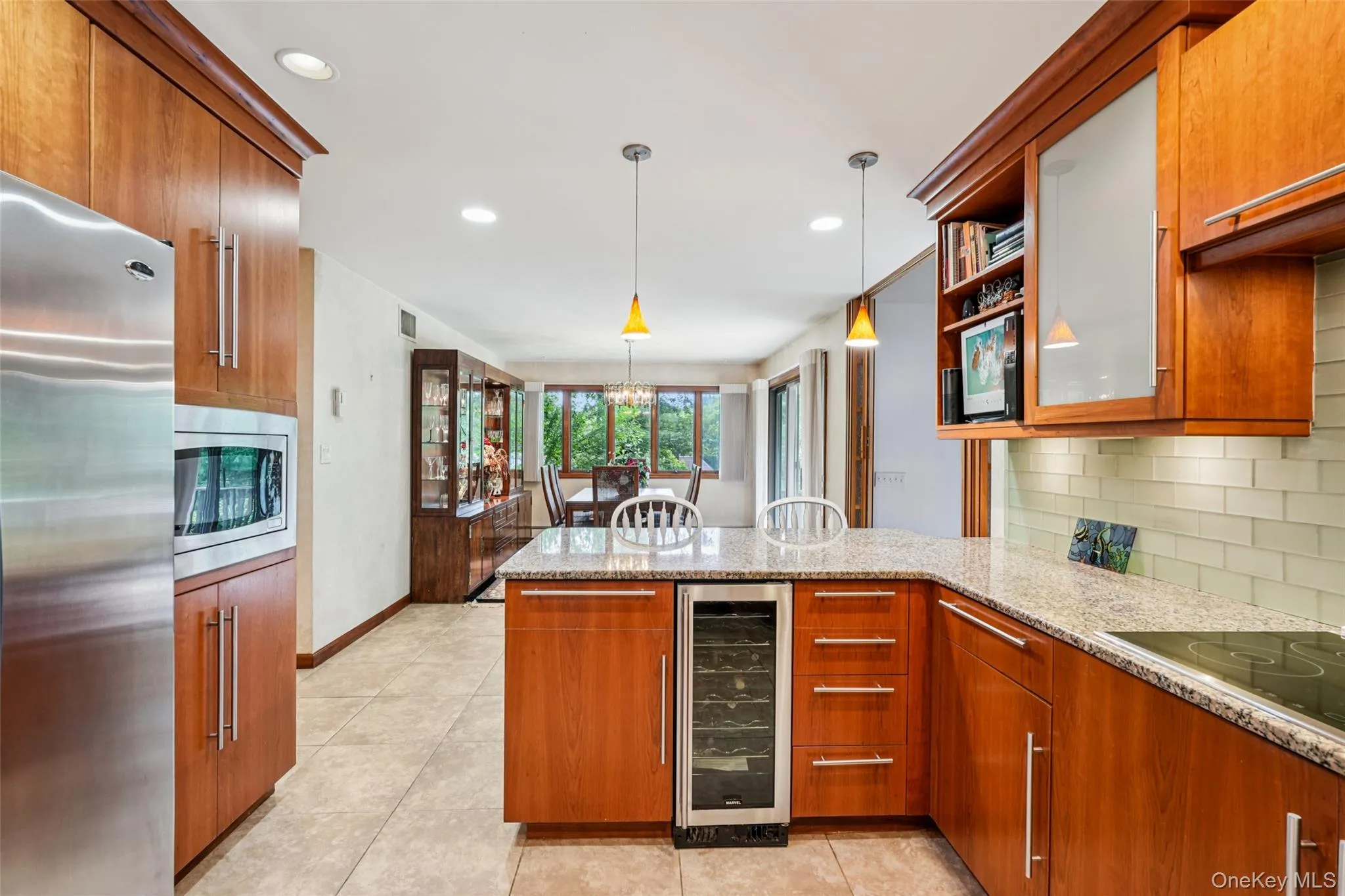 Kitchen with appliances with stainless steel finishes, wine cooler, a peninsula, decorative backsplash, and light stone counters Kitchen with appliances with stainless steel finishes, wine cooler, a peninsula, decorative backsplash, and light stone counters