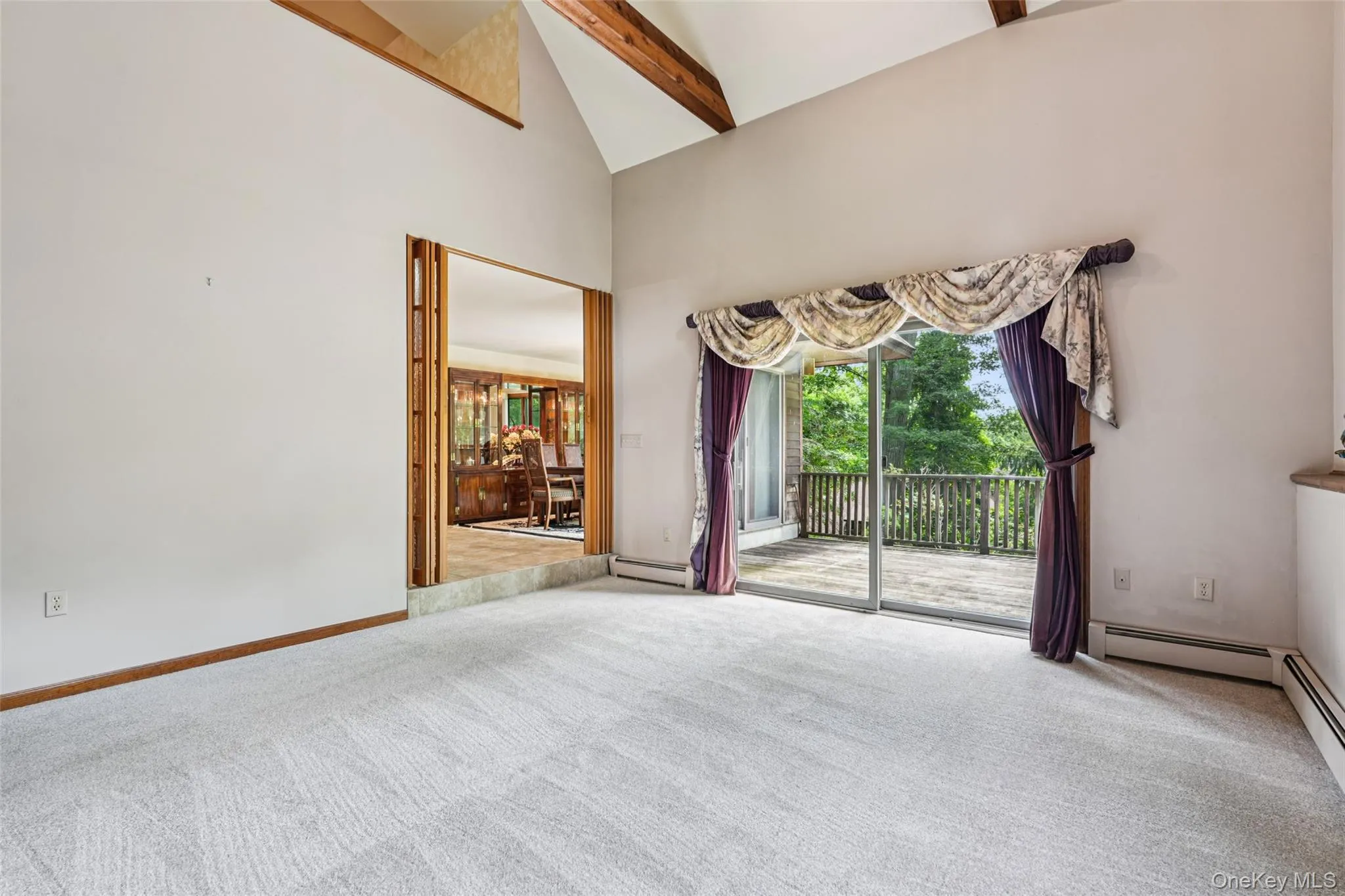 Spare room with carpet, baseboard heating, beamed ceiling, and high vaulted ceiling Spare room with carpet, baseboard heating, beamed ceiling, and high vaulted ceiling